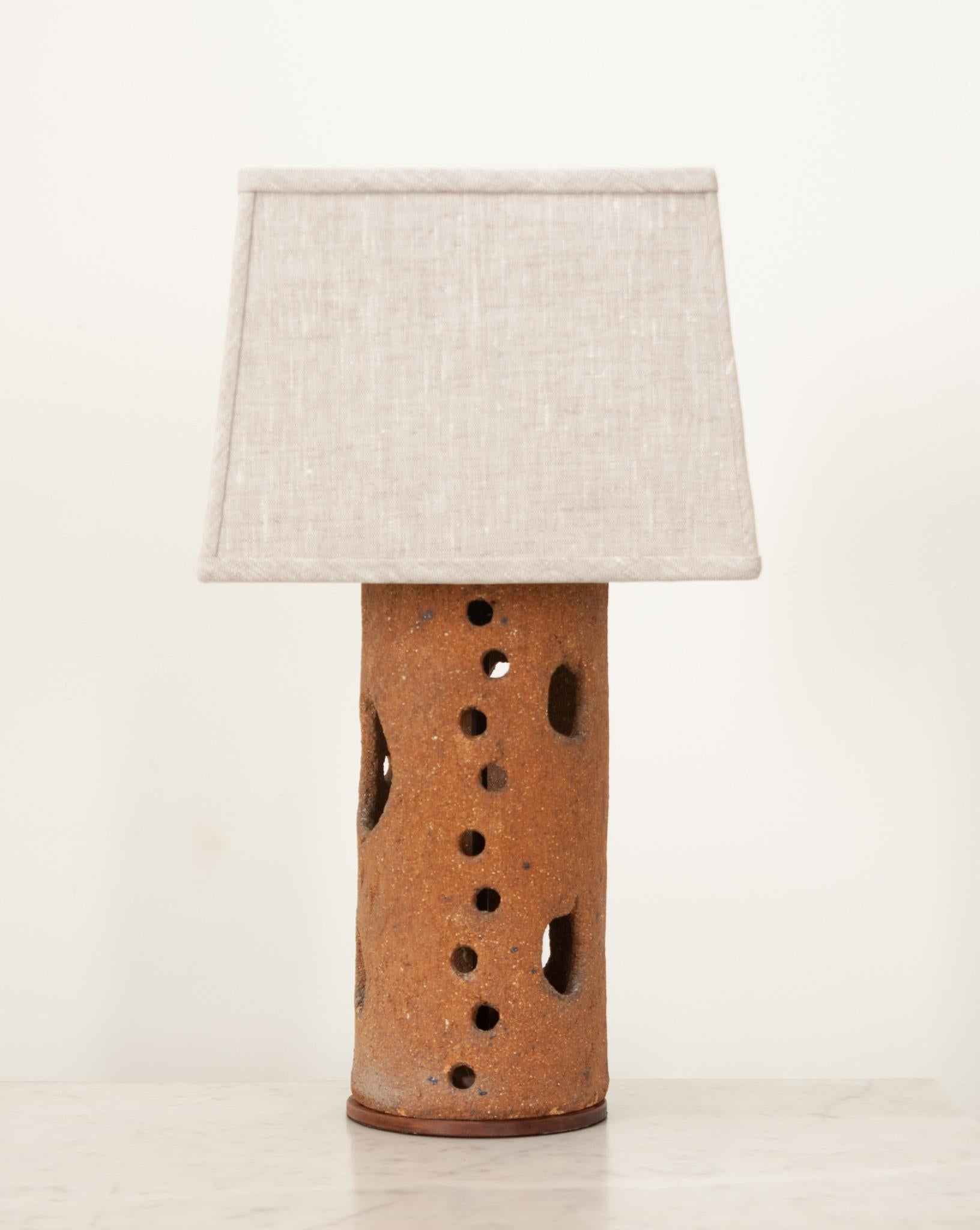 A wonderful terracotta vessel once used as a supporting cylinder in a pottery kiln now upcycled into a table lamp featuring a supremely tactile finish and custom made modern covered linen shade. Newly wired in the USA with all UL approved parts. Its