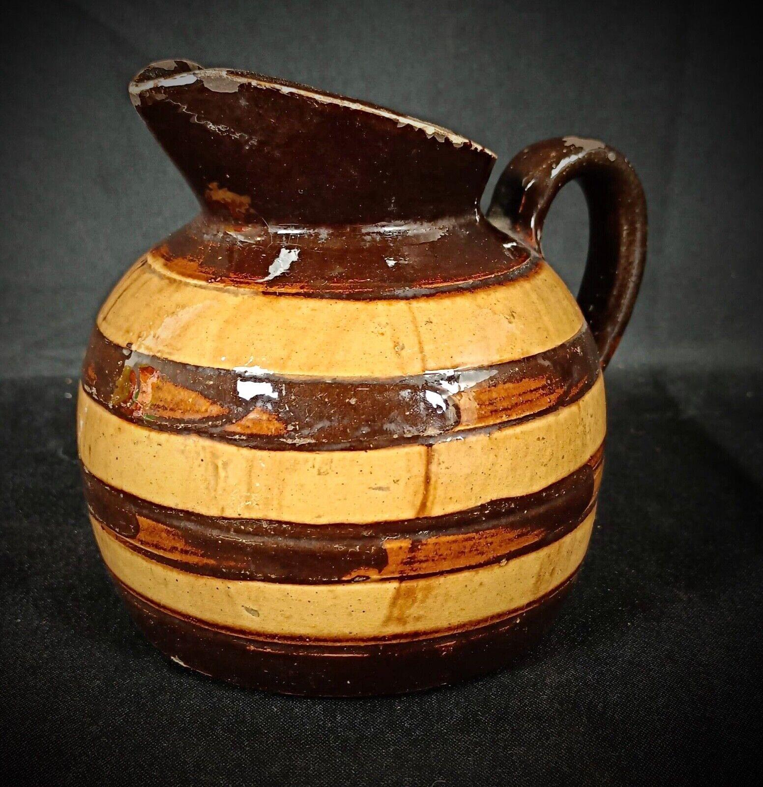 Apportez une touche de charme rustique à votre collection avec ce pichet vintage en argile peint à la main, conçu dans un style baril distinctif. Cette délicieuse pièce met en valeur l'art de l'artisanat traditionnel, ce qui en fait un ajout parfait