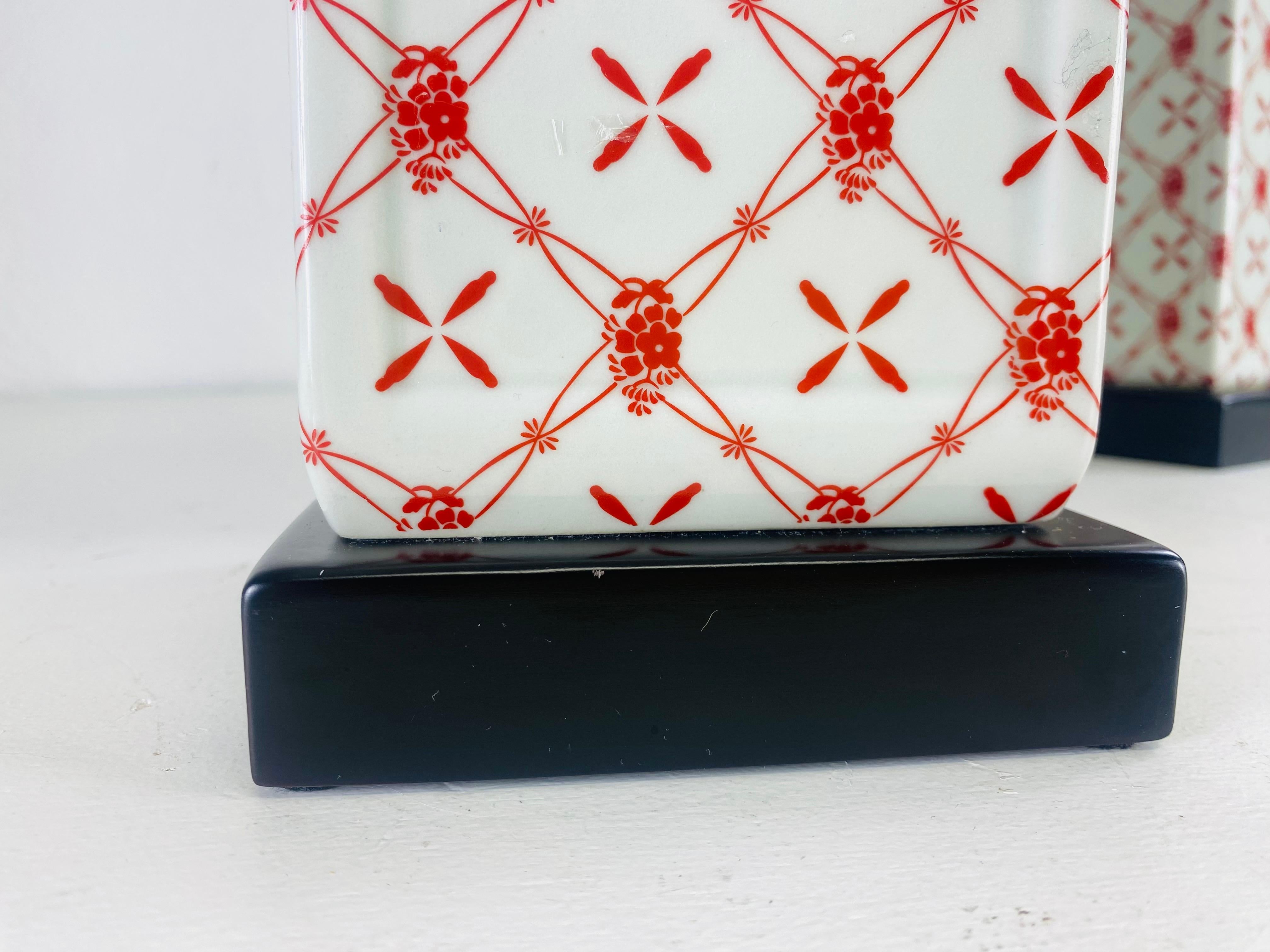 Voici une magnifique paire de chinoiseries peintes à la main.  lampes de table en poterie. Ces lampes de table ont un fond de couleur crème avec un motif floral géométrique peint sur la surface. Les lampes sont dotées d'une base noire et d'embouts