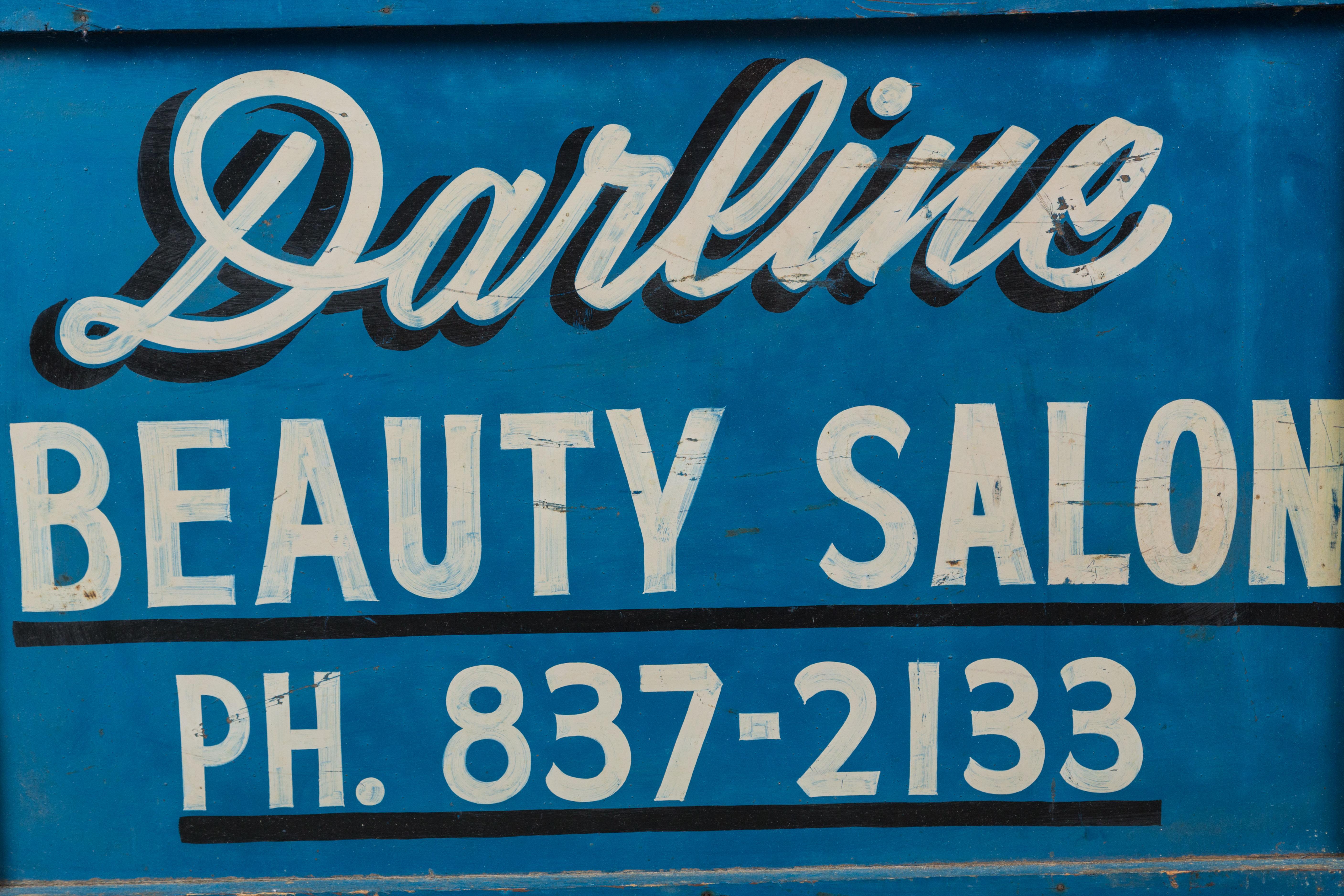 Late 1940s-1950 beauty salon sign. Graphic blue and white paint surface. Painted by the hand of a professional sign maker. Old vintage metal fasteners on each joined corner.