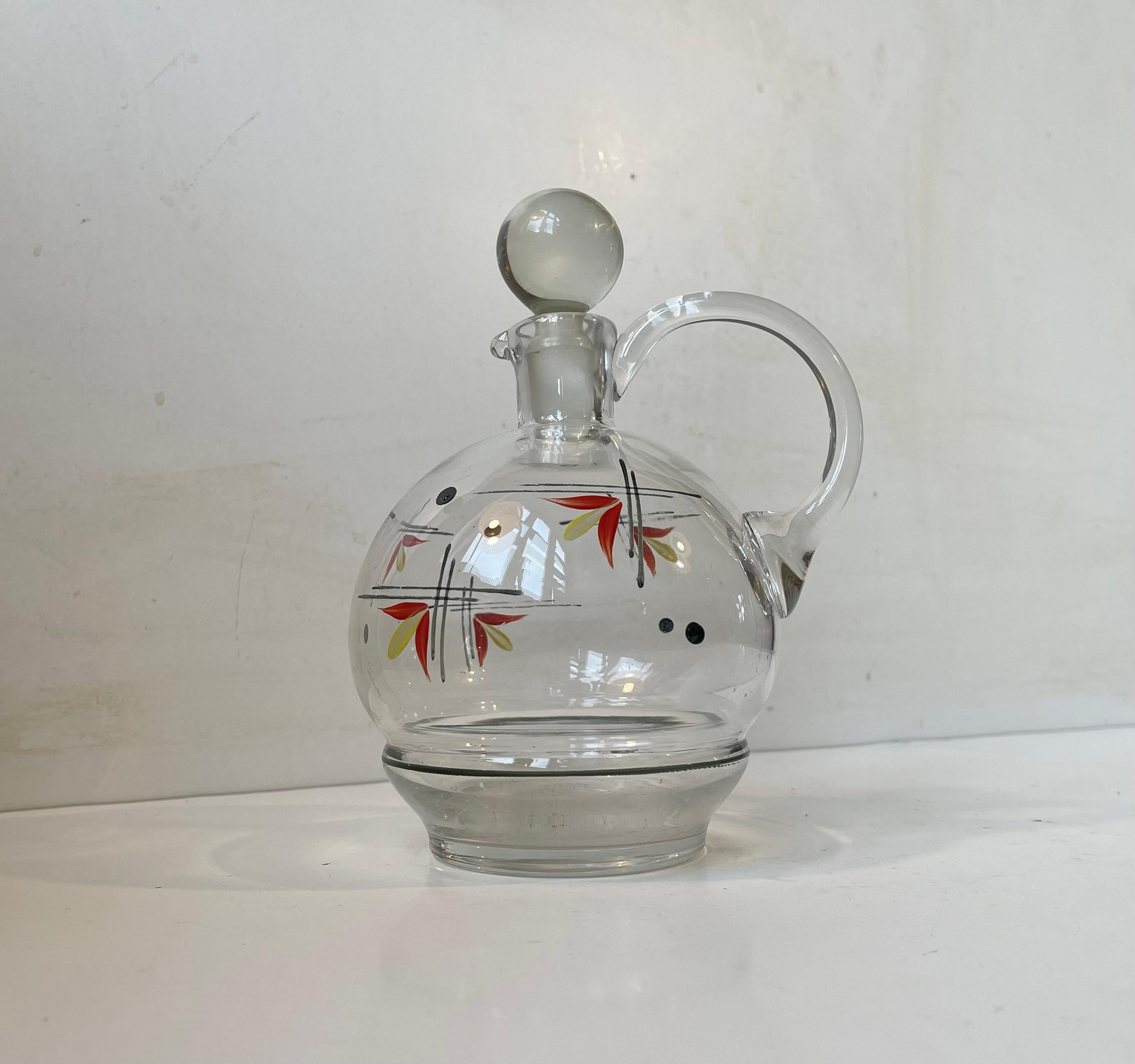 Art glass decanter with handle and hand-painted flowers in enamel lacquer. Designed by Jacob E. Bang, Arne Bang's kid brother, and made at Kastrup/Holmegaard in Denmark circa 1950-60. Measurements: H: 19 cm, D: 12 cm. Capacity: 0,6 liters approx.