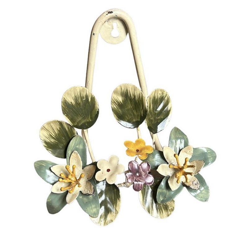 A vintage tole hand-painted hanging easel with a gorgeous flower motif. This small easel will be great to hold a decorative plate or book. It is created from metal and features a bouquet of flowers in green, purple, yellow, and cream. The back of