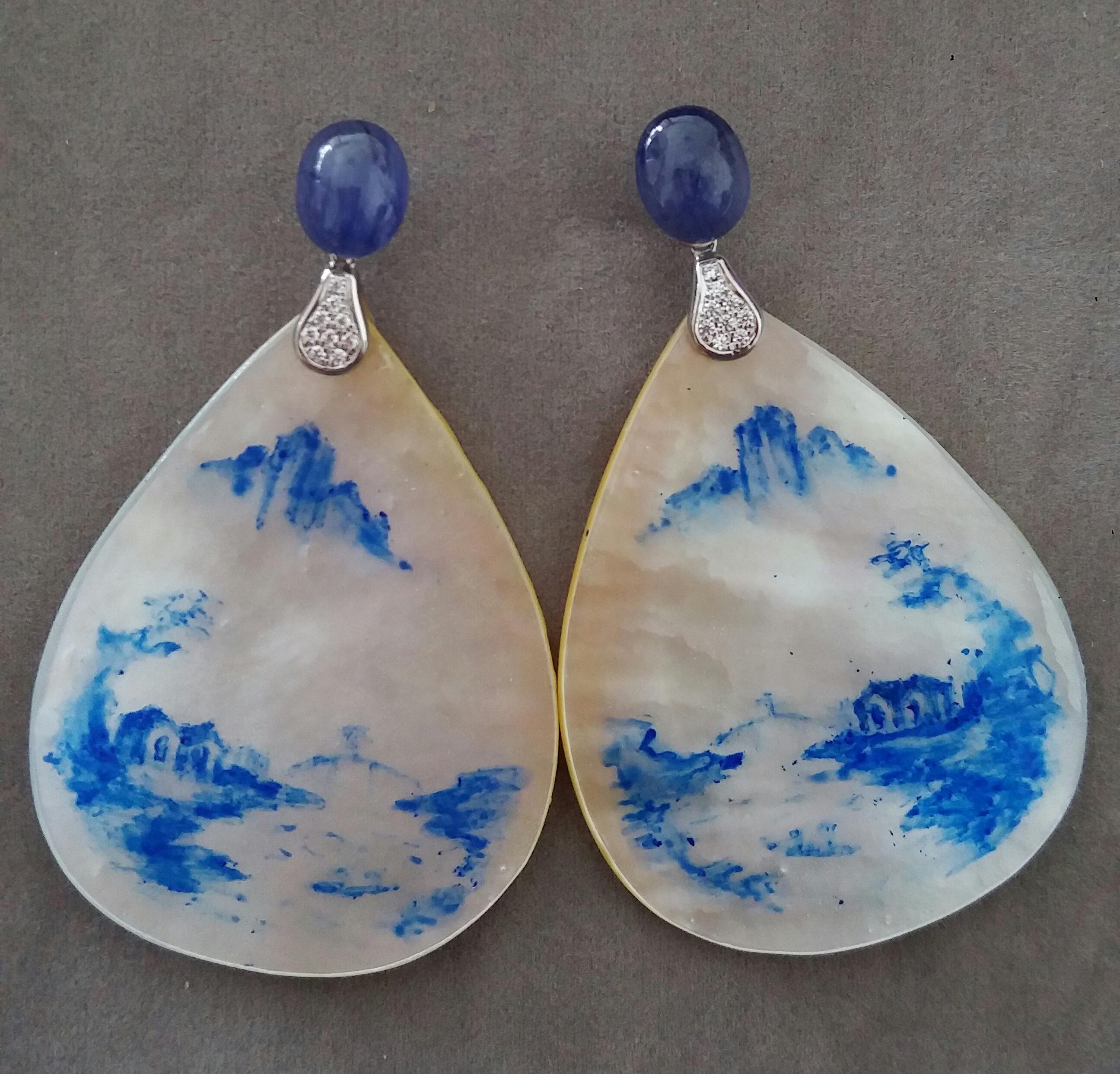 Vintage pair of hand painted pear shape Mother of Pearls  measuring 40x55 mm depicting a landscape with  houses on the river  and mountains in the distant background ,suspended from 2 Blue Sapphires Oval cabs measuring  8x10 mm  by 2 elements in 14