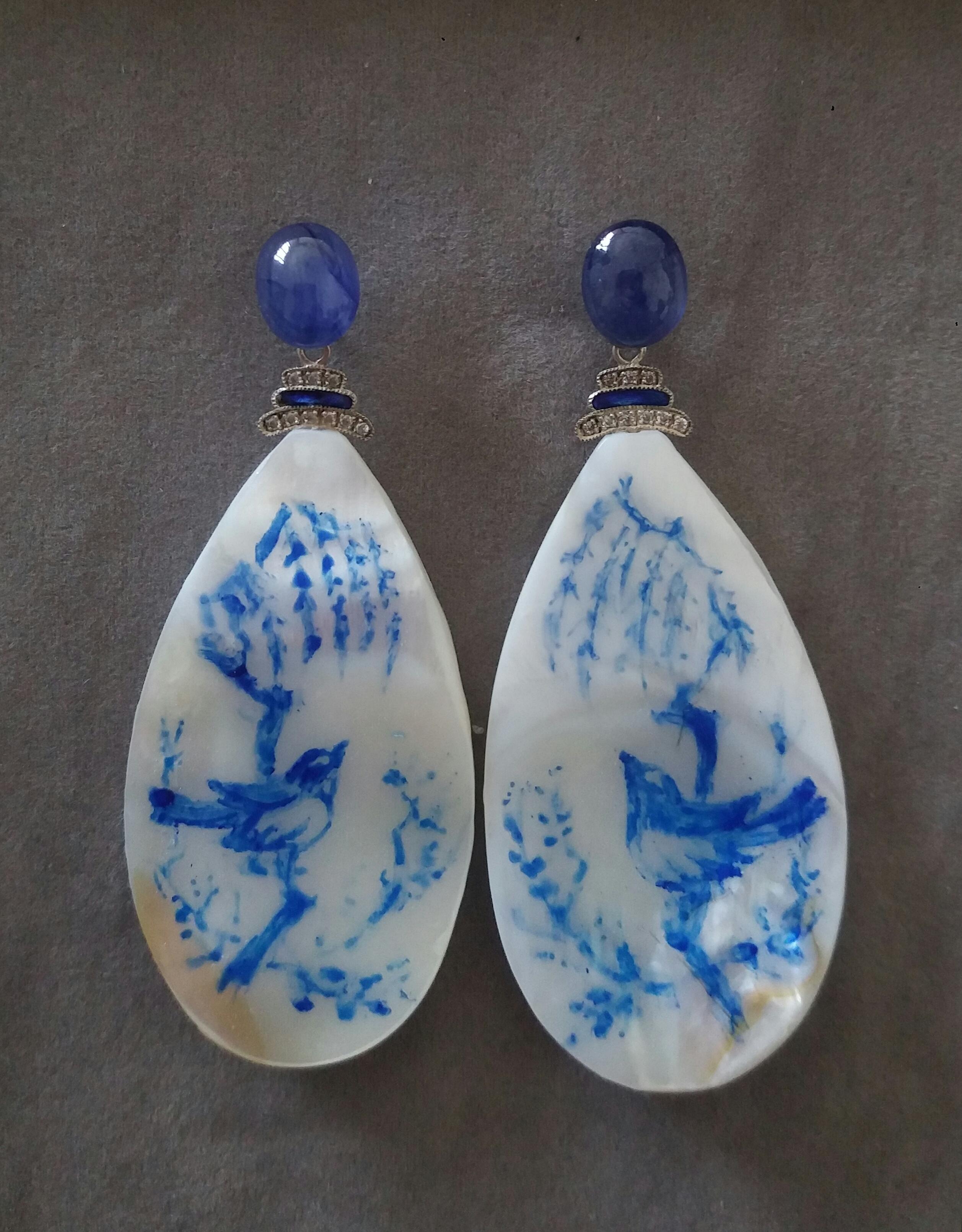 Vintage pair of hand painted pear shape Mother of Pearls  measuring 30x55 mm depicting a bird on a tree branch with a rich foliage ,suspended from 2 Blue Sapphires Oval cabs measuring  8x10 mm  by 2 elements in 14 K white gold ,enamel and 18 small