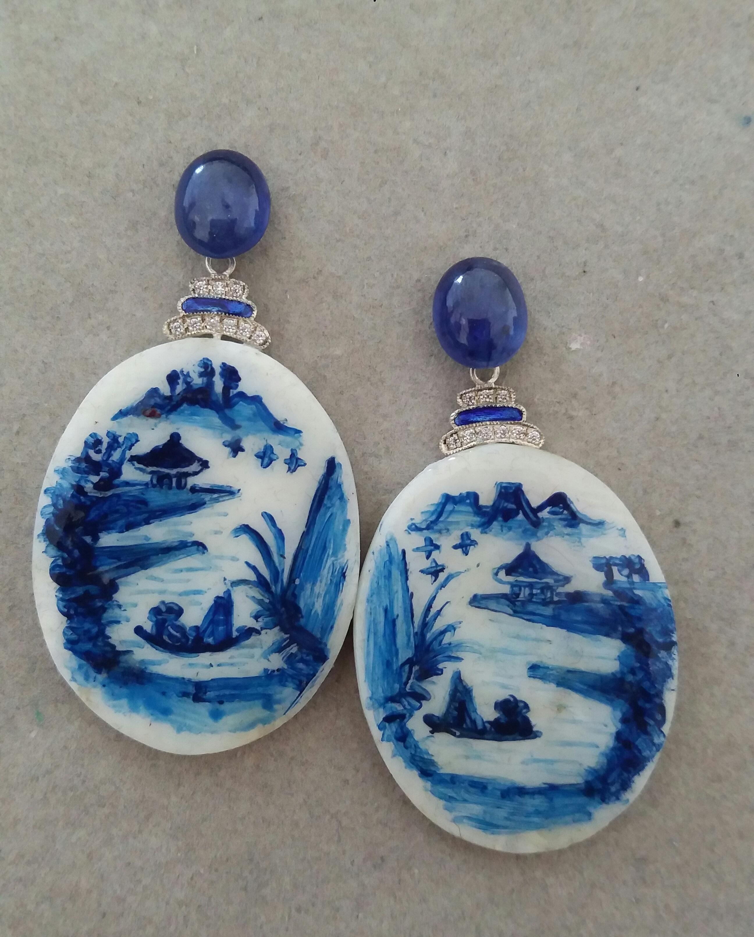 Vintage pair of hand painted oval shape Mother of Pearl  depicting a lake landscape with mountains and a temple in the background and 2 chinese fishermen on their boat ,suspended from 2 oval Blue Sapphire cabochons size 8x10 mm ,in the middle we