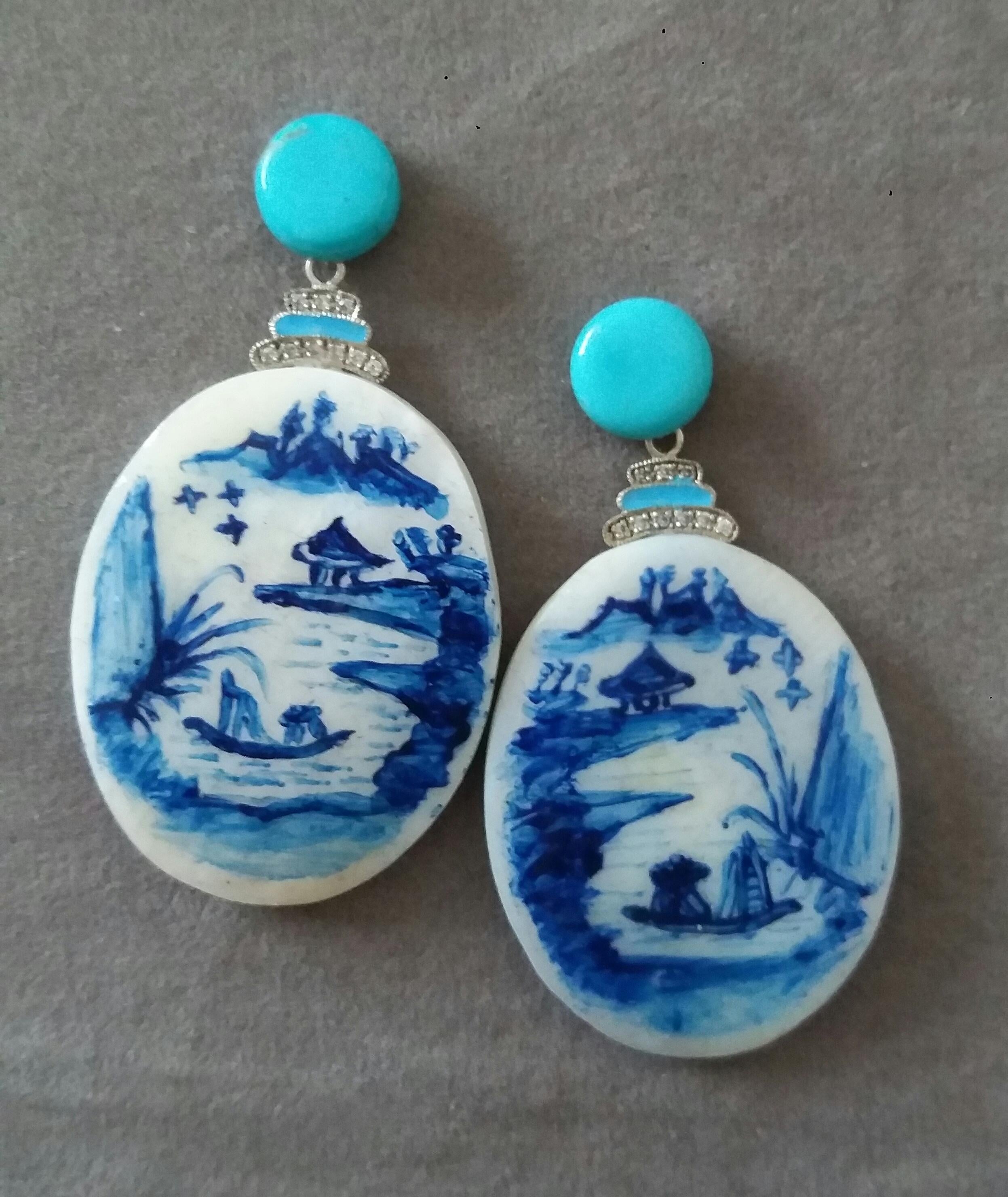 Vintage pair of hand painted oval shape Mother of Pearl  measuring 30x38 mm depicting a lake landscape with mountains and a temple in the background and 2 chinese fishermen on their boat ,suspended from 2 Turquoise buttons 10 mm in diameter,in the