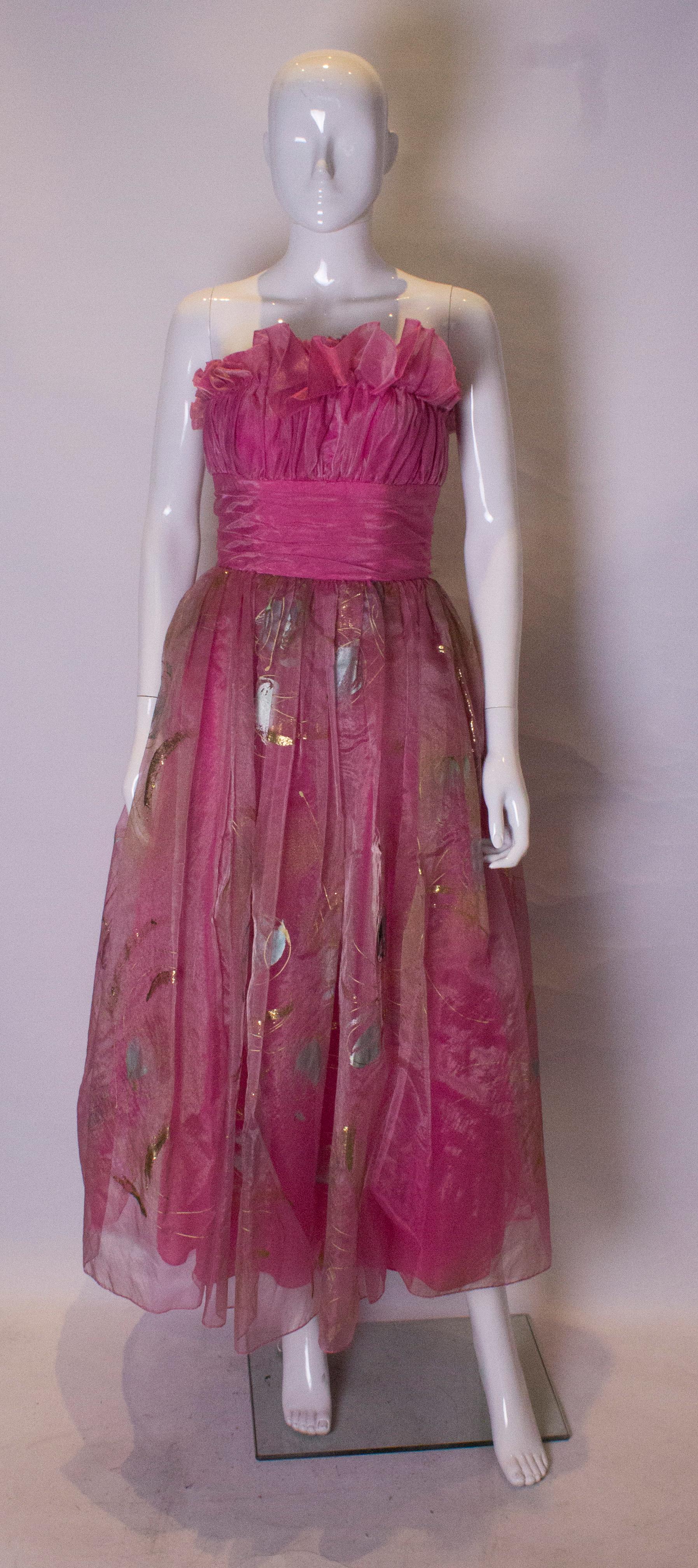 A stunning pink prom dress with a wonderful hand painted skirt.  The skirt is painted in an attractive print in gold , silver and  turquoise. The dress is fully lined and has a net underskirt.  It has a frill at the bust line and a central back zip.