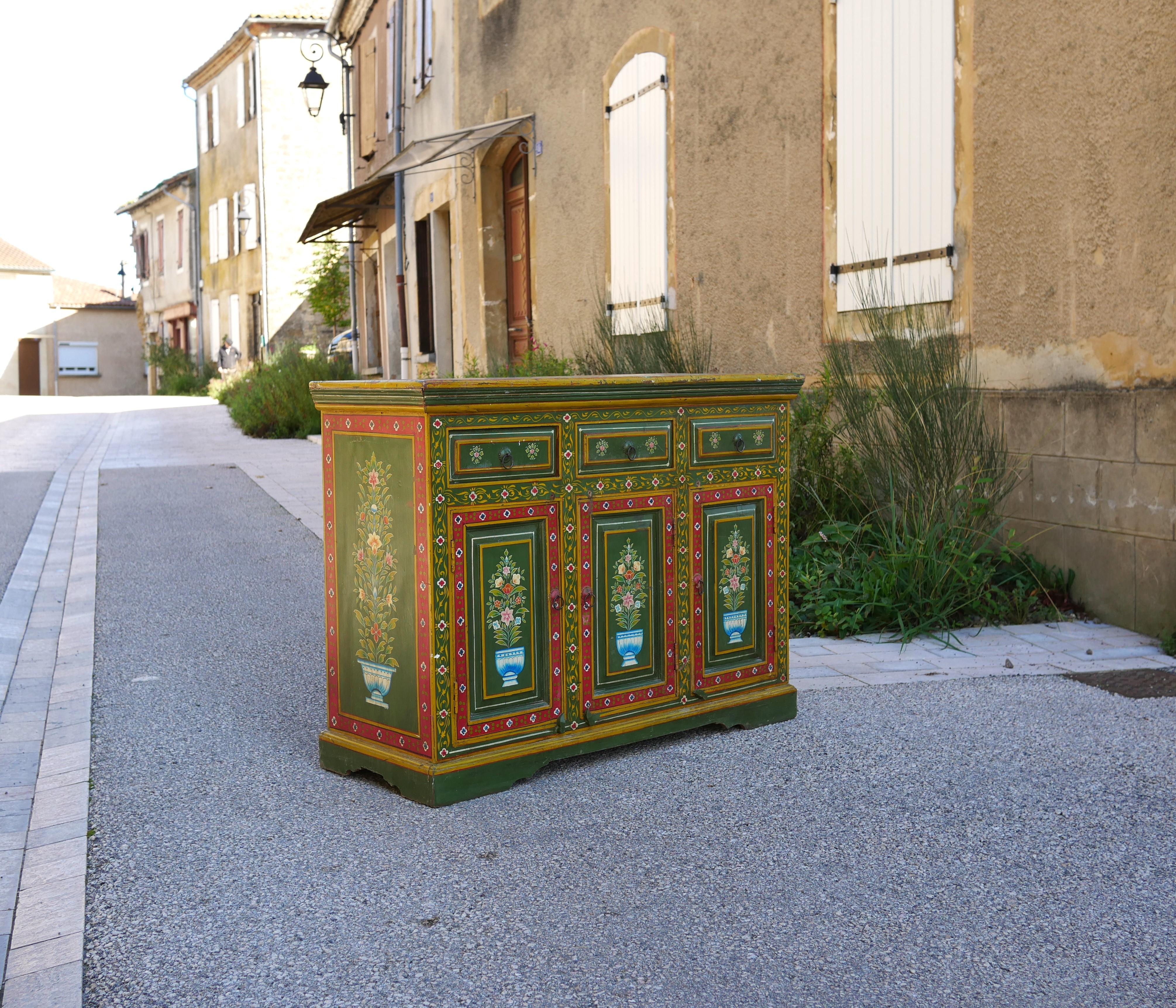 Aparador de madera de los años 90. 

Sus líneas son armoniosas y cálidas. Su estampado floral pintado a mano y su color verde le dan mucho carácter y elegancia.

Estético, amplio y práctico, el bufé quedará perfecto en la cocina, en el comedor, en