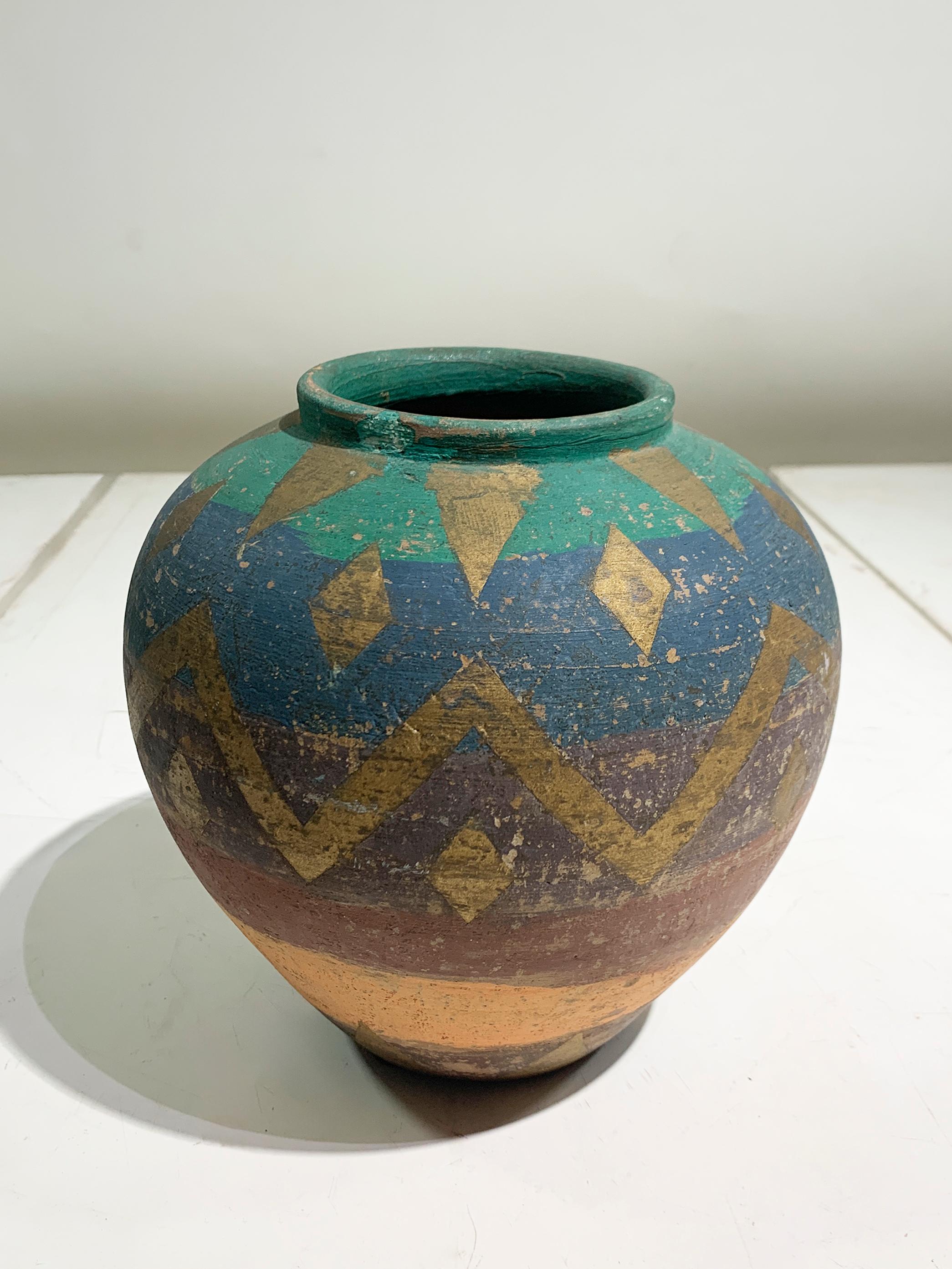 Un vaso in terracotta di grande impatto visivo risalente al 1960 circa, che si distingue per la sua ricca tavolozza di colori e il suo audace motivo grafico. Il vaso presenta una classica e attraente forma a bulbo con un bordo leggermente svasato,