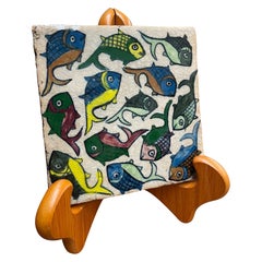 Tile vintage peint à la main avec un motif de poissons nageant.