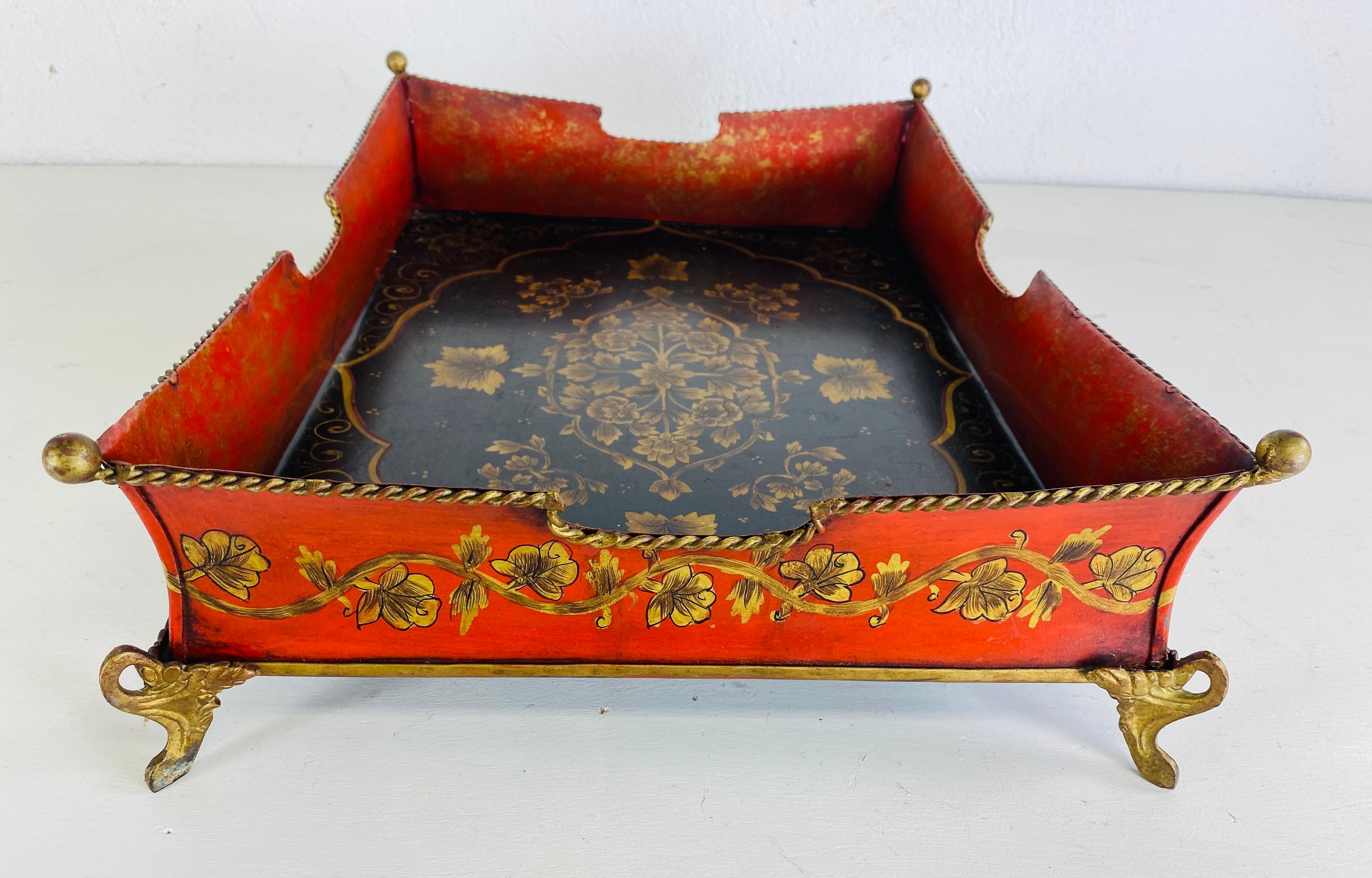 Se trata de una bandeja de galera vintage pintada a mano. La bandeja galera tiene decoración floral pintada a mano alrededor del borde en rojo y dorado. La bandeja se apoya sobre cuatro patas doradas ornamentadas de estilo eduardiano. El interior de