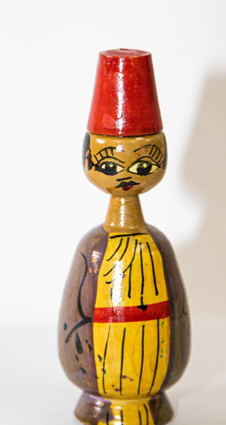 Stylized wooden figurine, sculpture of a man with traditional period clothes and a red Fez hat.
Vintage hand-painted wood spindle doll with abstract and naive design.
Hand Made Folk Art Made in Egypt. Circa 1950.
hand--crafted and hand painted
