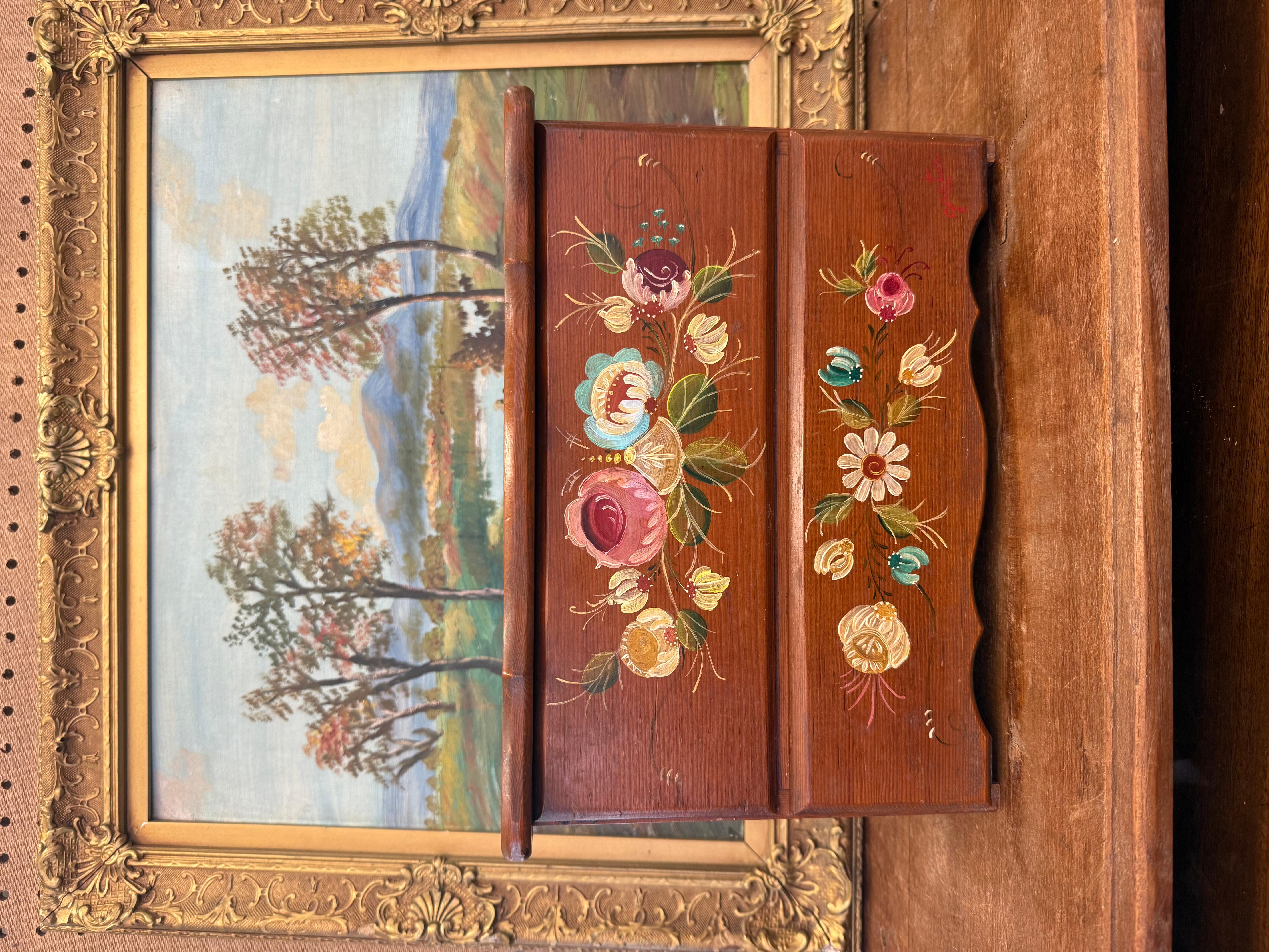 This charming vintage wooden jewelry box features hand-painted floral designs in a traditional folk art style. With vibrant, delicate flowers adorning the front and top, this rustic wooden chest is both a functional storage piece and a beautiful