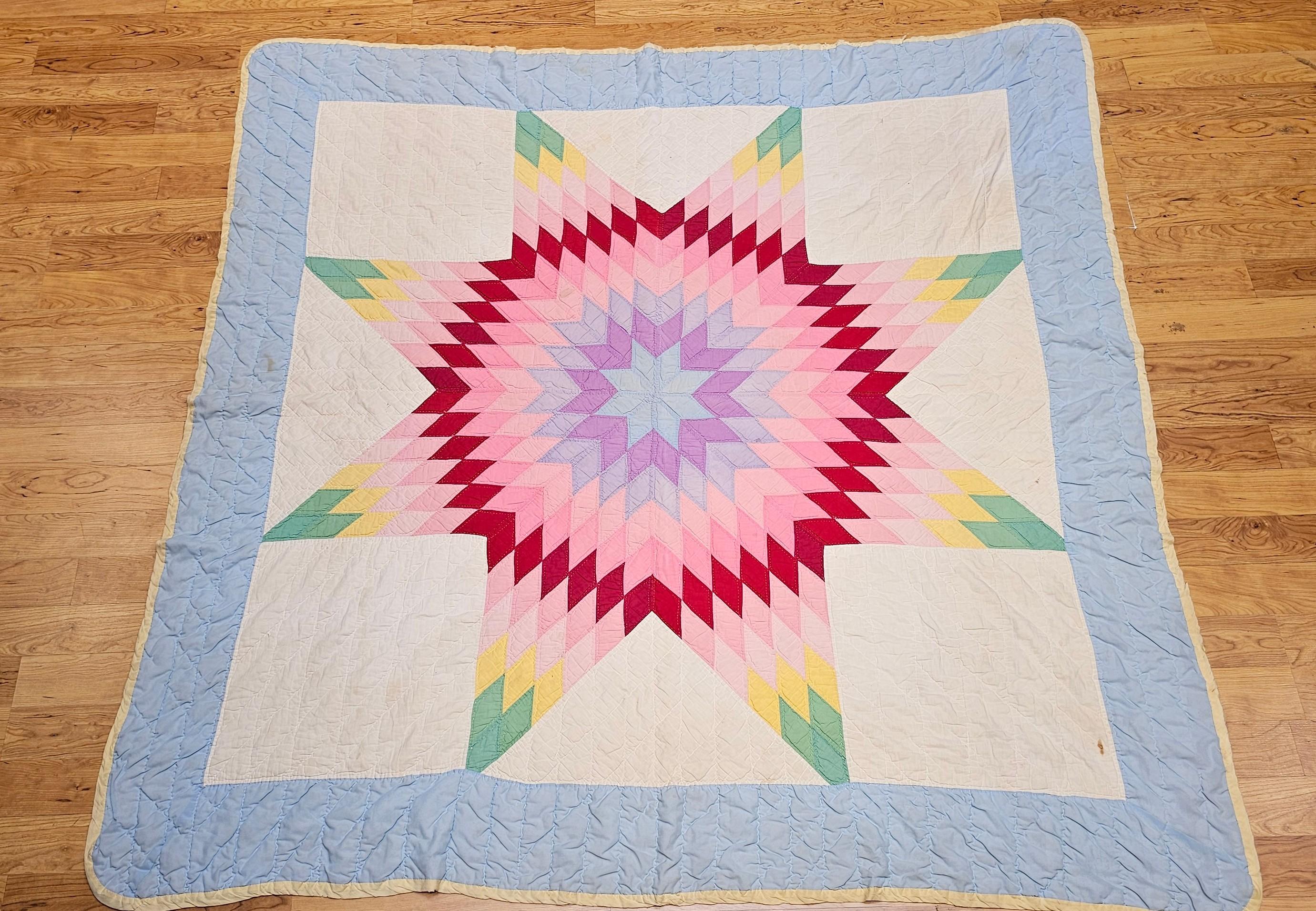An exquisite early 20th-century Lone Star quilt, entirely hand-stitched and hand-quilted, showcasing a radiant central star motif on an ivory ground with a delicate baby blue border. The star design bursts with brilliant shades of green, yellow,