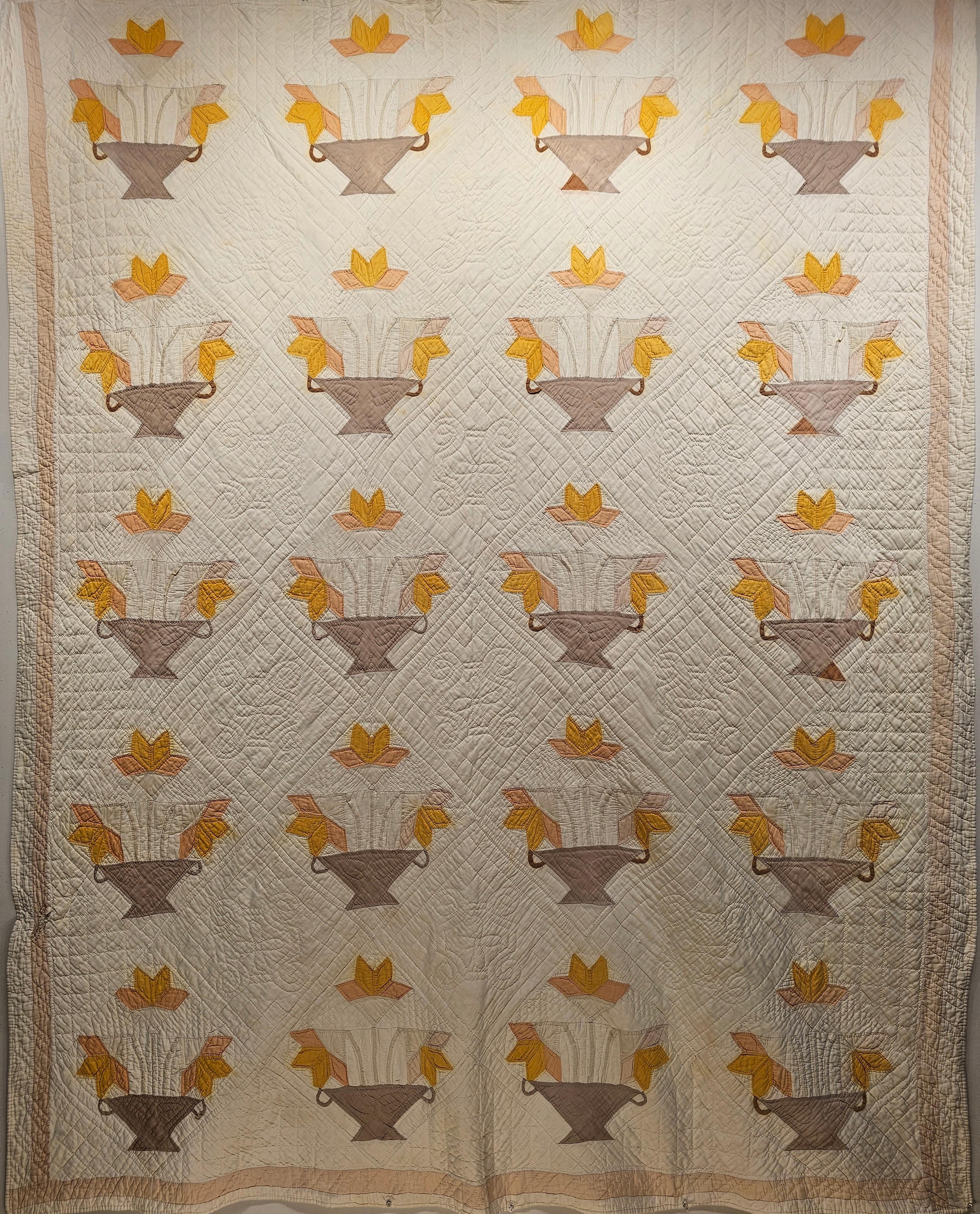 This beautiful American Applique Quilt was hand stitched in the early part of the 20th century. The American Applique Quilt is in a “Basket” pattern with the basket in brown color and the flowers in yellow, pink, and ivory on an ivory background. 