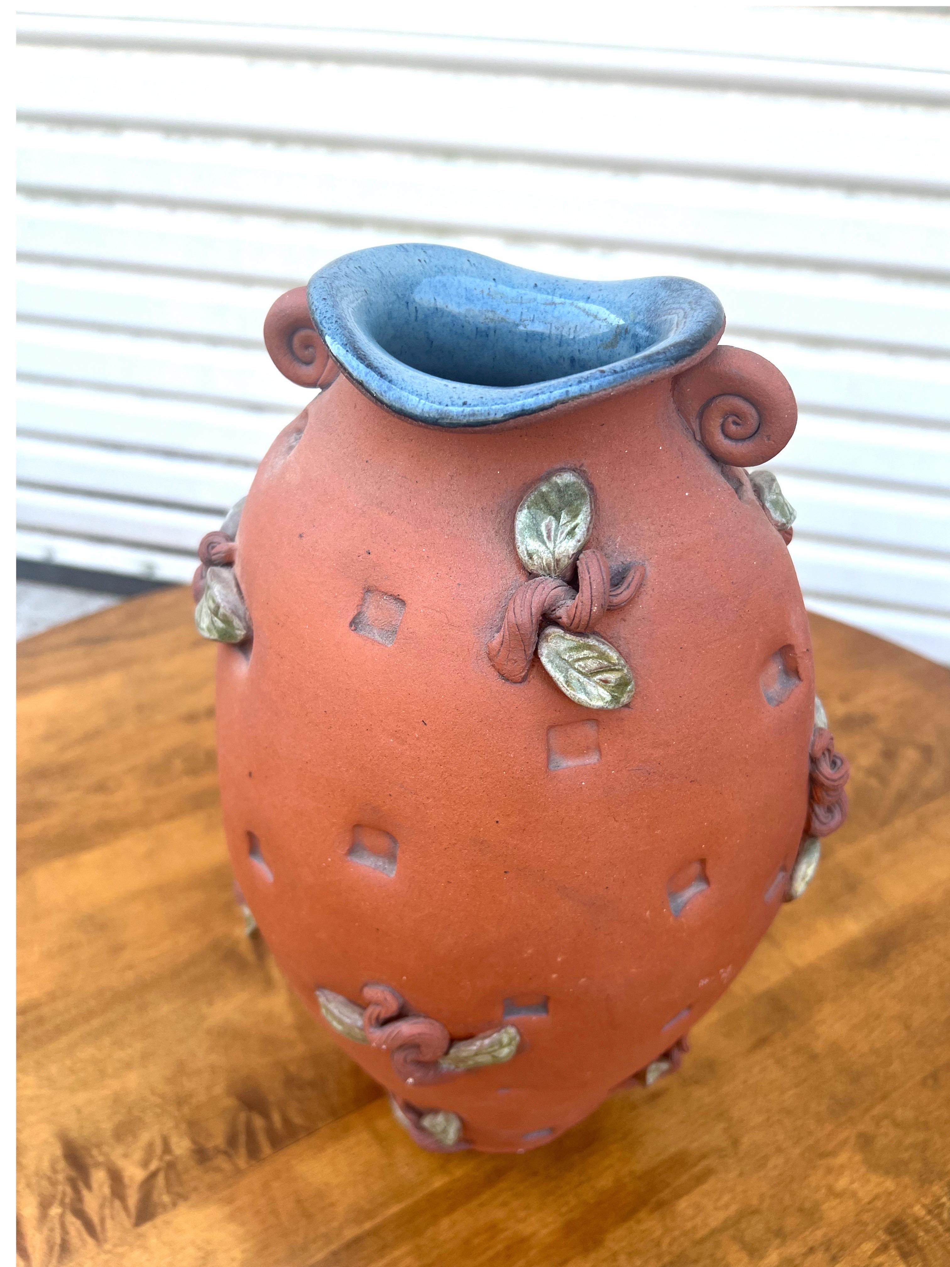 Ce superbe vase en terre cuite de studio pottery présente de belles feuilles et tiges appliquées.  L'intérieur du vase est recouvert d'une belle glaçure bleue, ce qui crée un joli contraste.