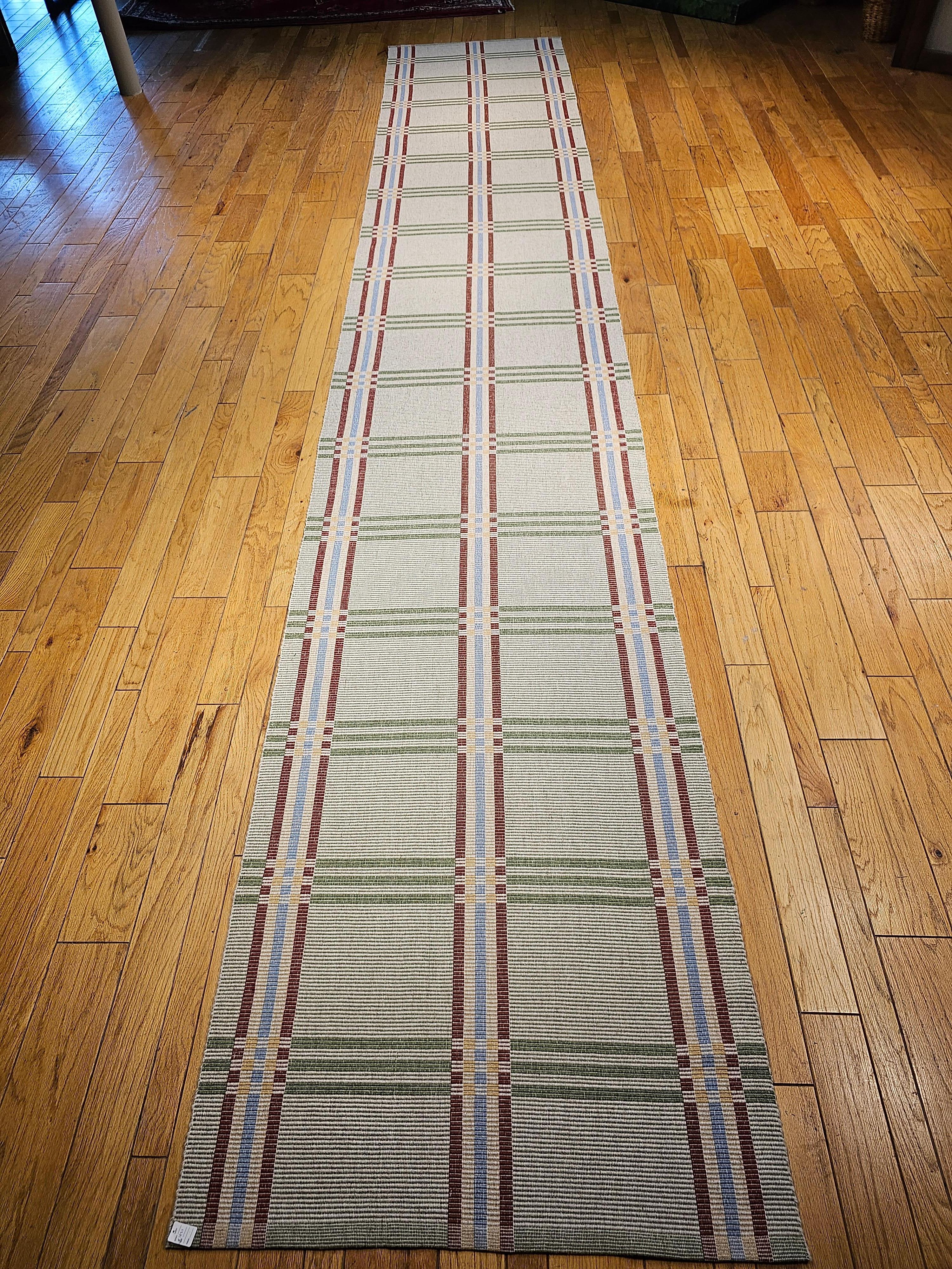 A vintage American flatwoven wide runner from the late 1900s in baby blue, red, yellow, green and wheat colors.  The runner has a wheat color background with vertical stripes in baby blue, red and yellow and horizontal stripes in green.  Because the
