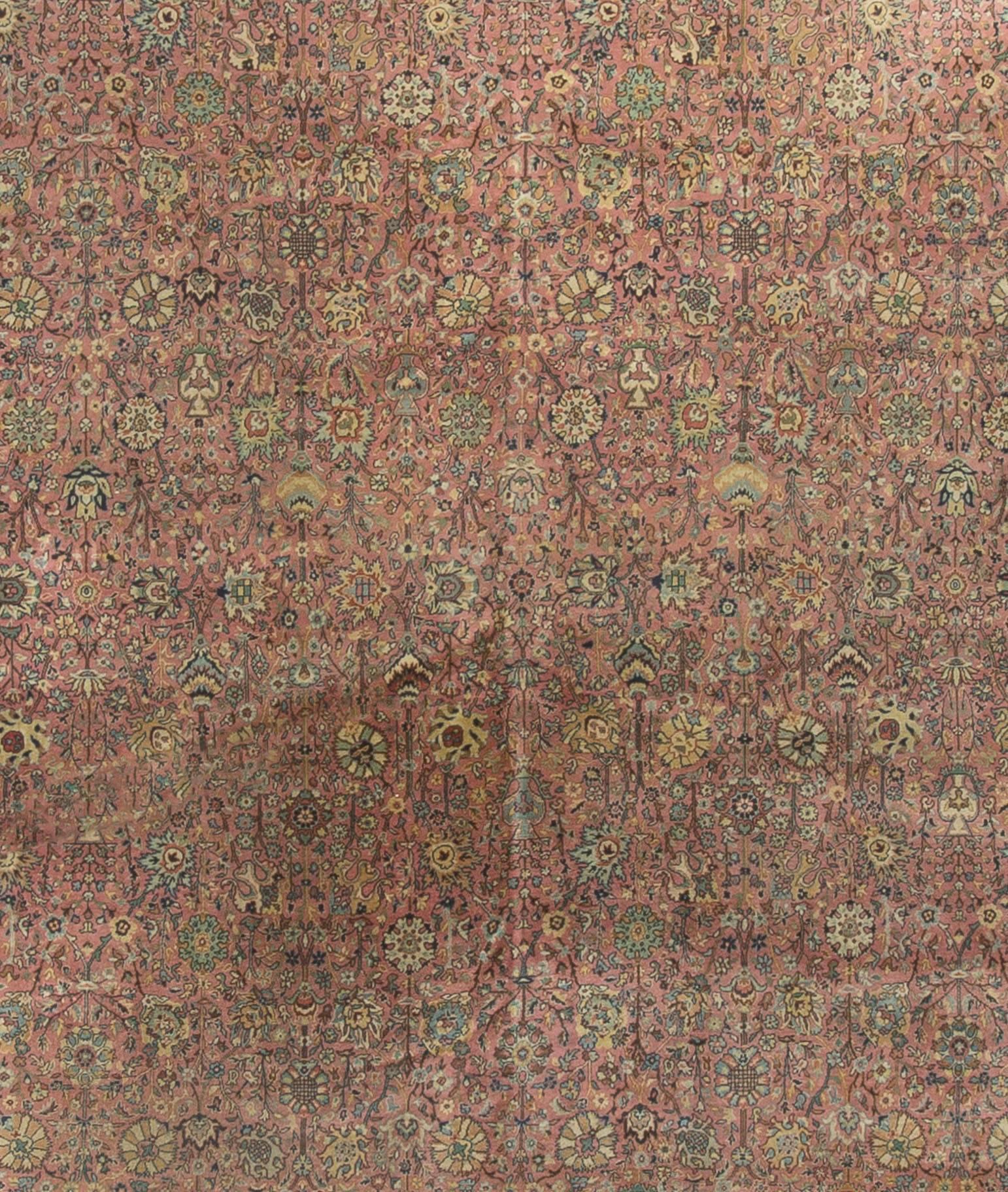 Dieser handgewebte Teppich aus Indien stammt aus den 1920er Jahren. Das Hauptfeld ist mit floralen Motiven gefüllt, die von einer elfenbeinfarbenen Umrandung umgeben sind, die das florale Thema fortführt. Größe: 9'10 x 13'2.