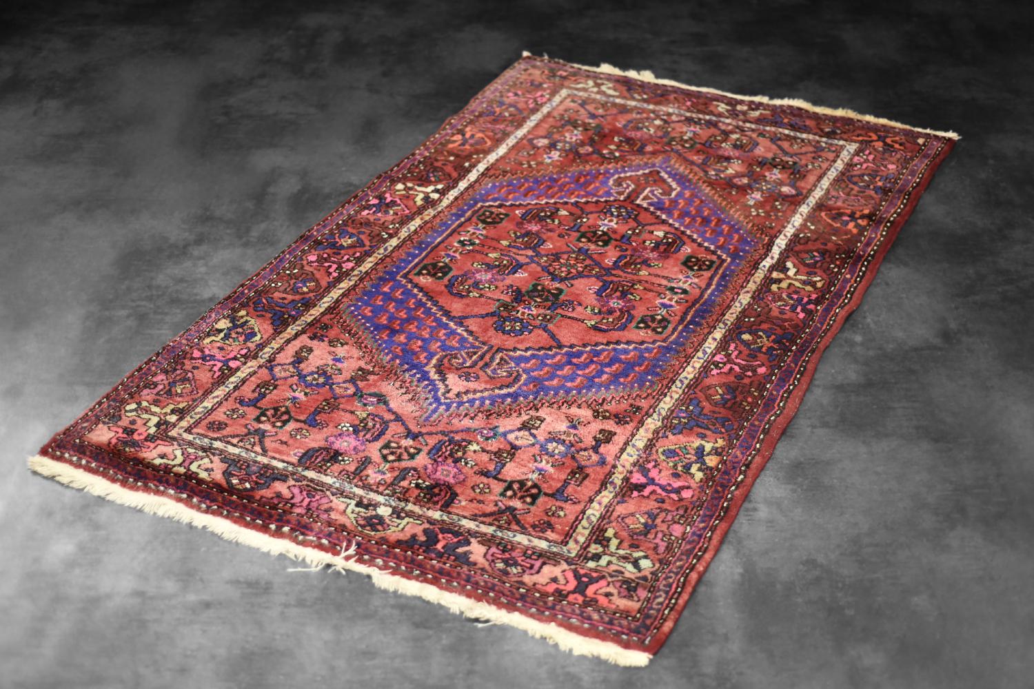 This hand-woven oriental Hamadan rug was made in Iran during the 1960s. It is flat woven carpet - woven using traditional technique. This rug is dyed in shades of rustic red, pink and purple with a strongly accentuated, single medallion, placed in