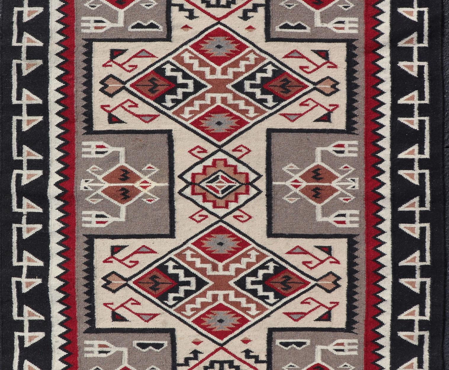 Vintage hand woven Navajo style rug in gray, ivory, black, and red.  Rug/ X23-0104, country of origin / type: America / Navajo, circa 1980
Measures : 4'0 x 6'0
This intriguing vintage Navajo rug was woven during the late 20th century. The exciting