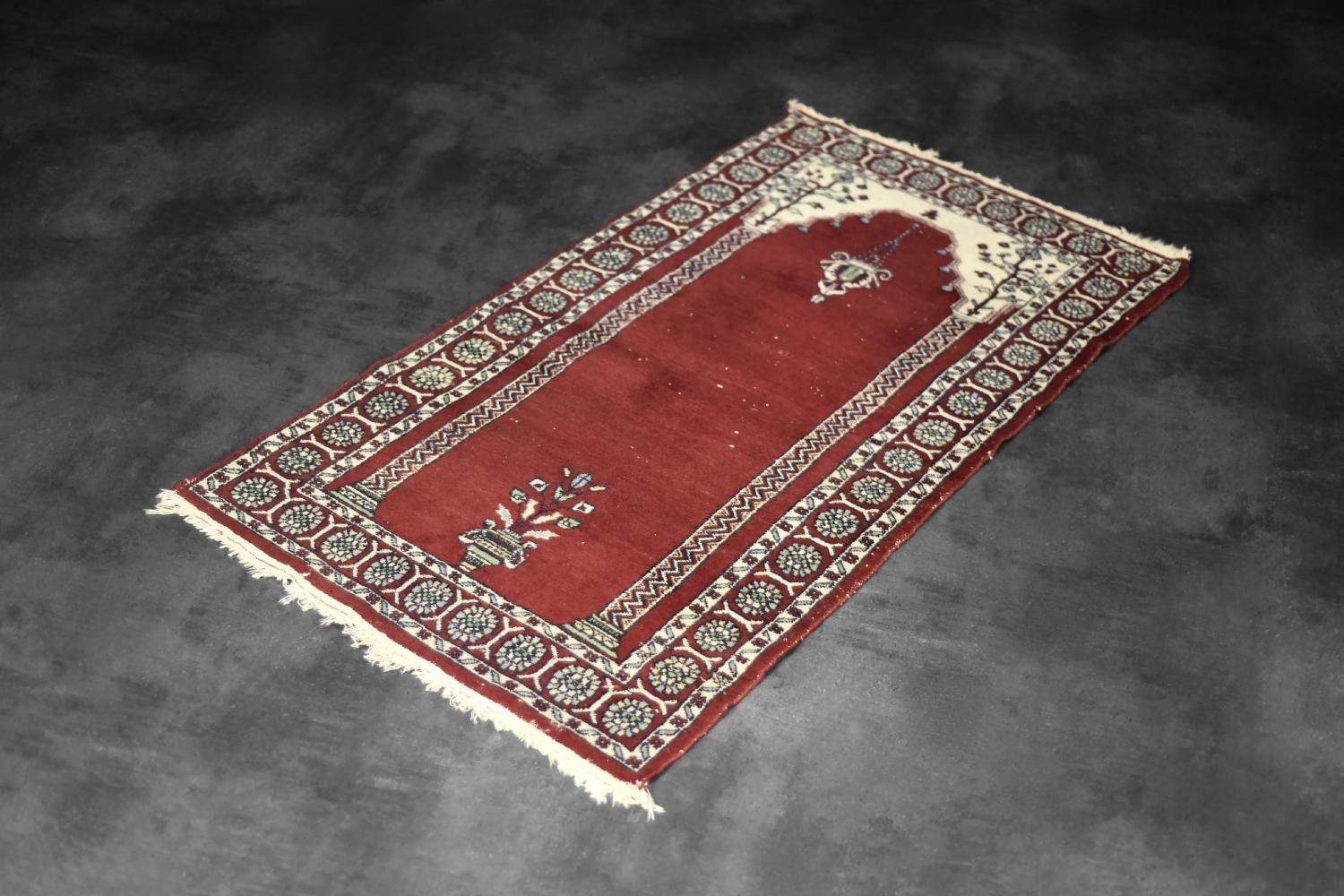 This hand-woven Mihrab prayer rug was made in Pakistan during the 1960s. Traditionally flat-woven and dyed in shades of red and beige, Mihrab rugs are a type of prayer rug used by Muslims during prayer. They are characterized by a specific pattern