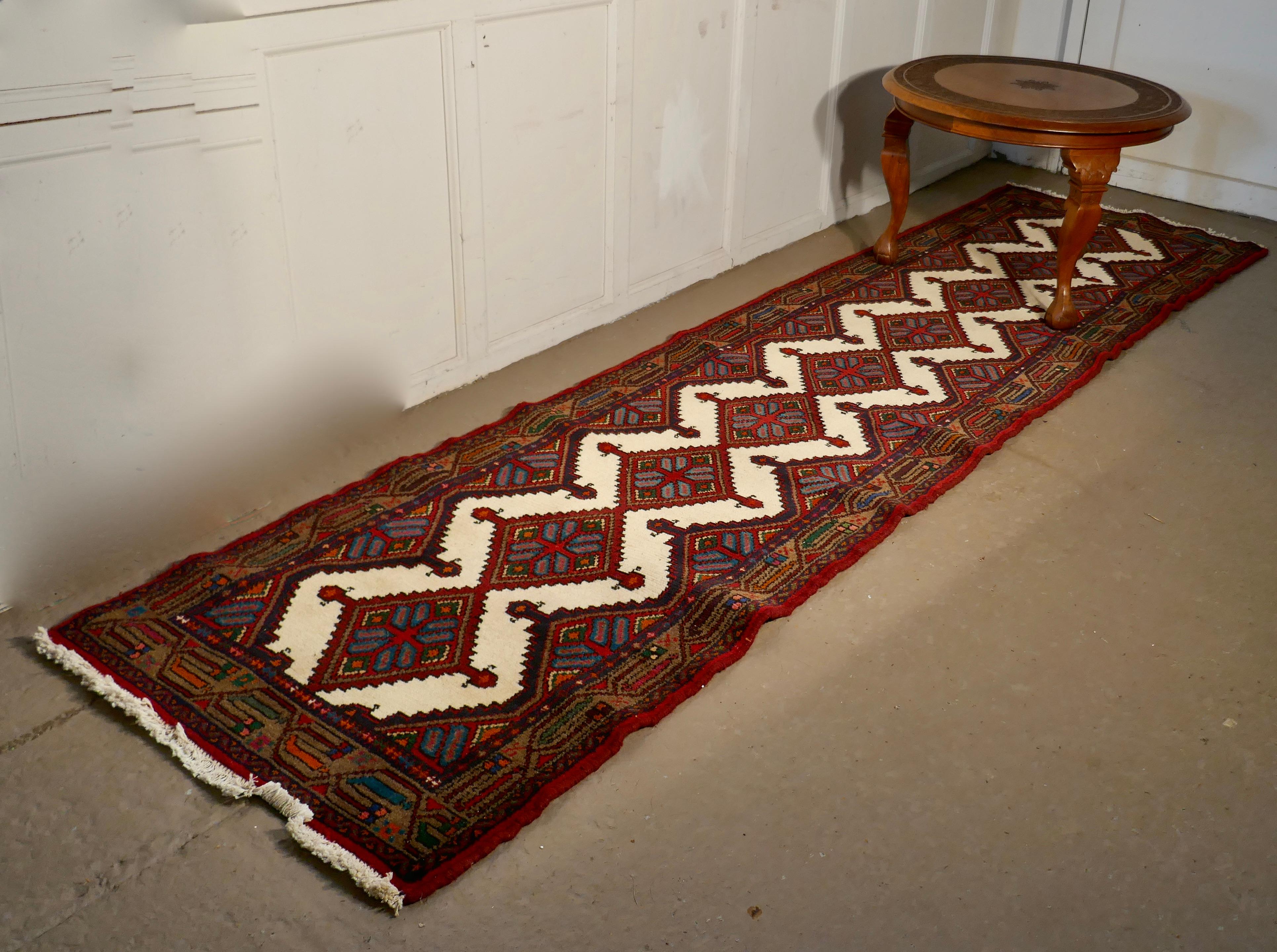 Vintage Hand Woven Persian 10ft Carpet Runner

A superb looking piece dating from around 1930 and has a lovely colour palette of deep red with ecru, blue and orange
The Wool Runner has 5 lozenges along its length with ecru fringes at both ends
