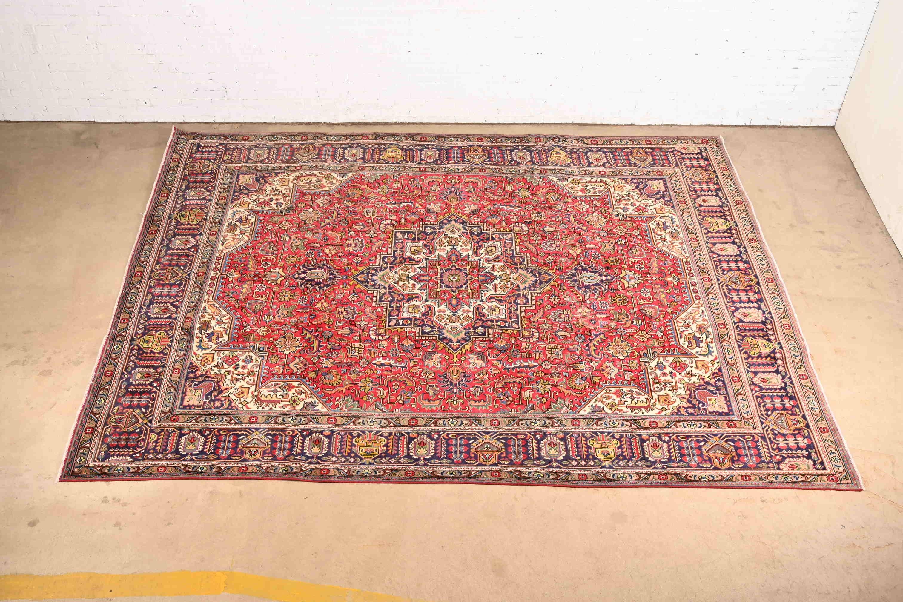 Uno splendido tappeto persiano d'epoca annodato a mano in lana Heriz, per una stanza, di dimensioni ragguardevoli.

Circa metà del XX secolo

Presenta un bellissimo motivo geometrico tribale, con colori predominanti rosso, blu e avorio.

Misure: