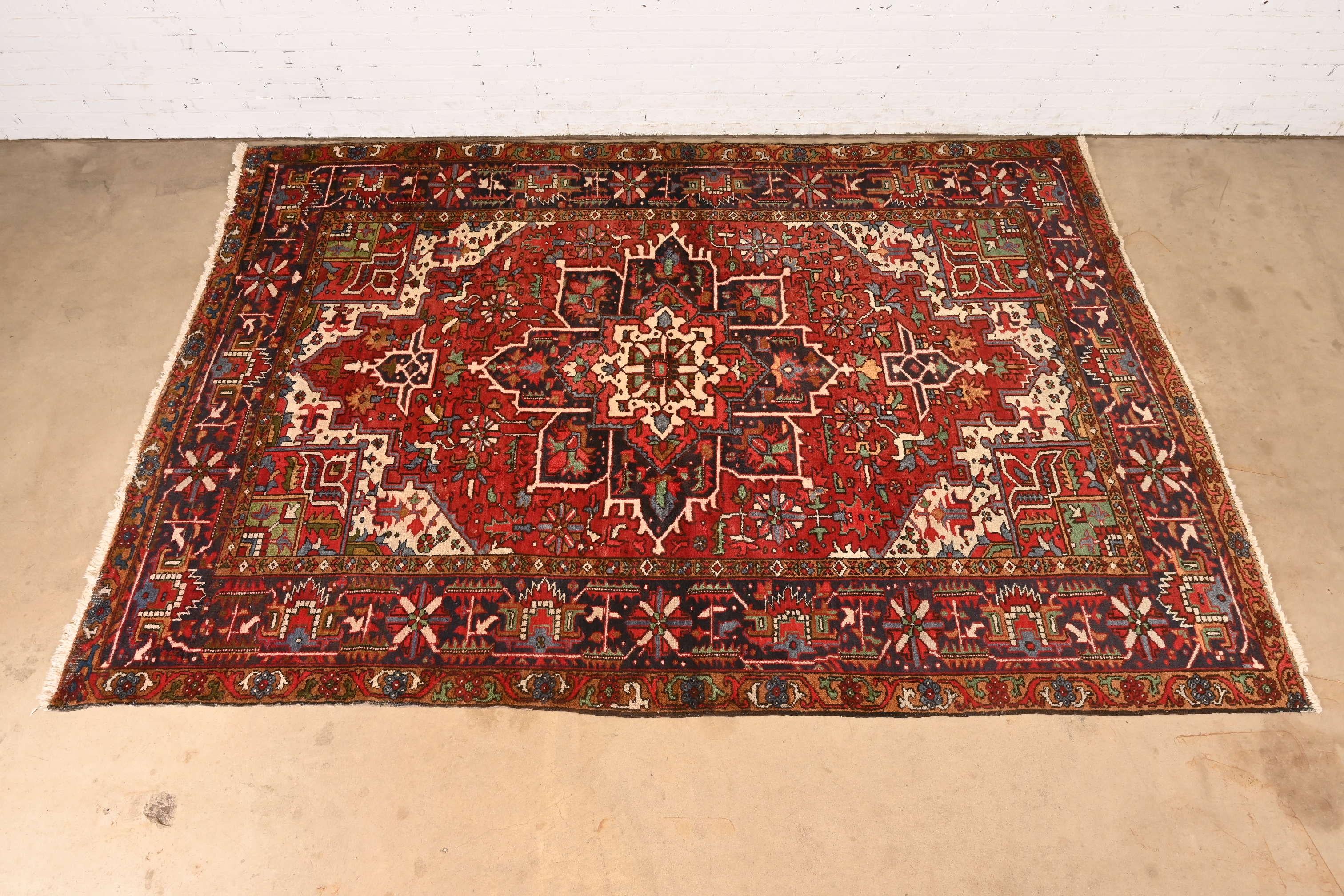 Uno splendido tappeto persiano d'epoca annodato a mano in lana Heriz, per una stanza, di dimensioni ragguardevoli.

Circa metà del XX secolo

Presenta un bellissimo motivo geometrico tribale, con colori predominanti in rosso, blu, nero e