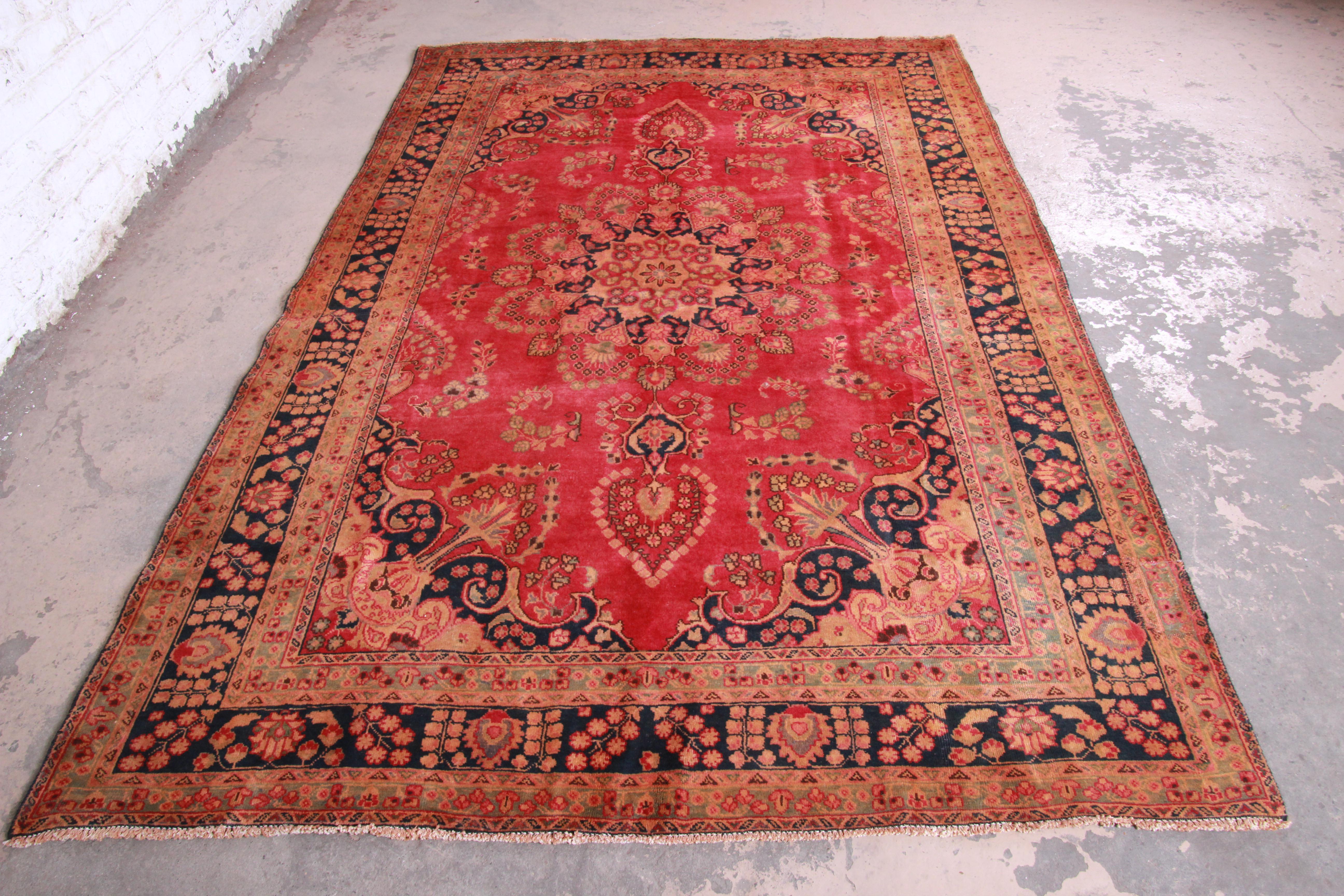 A gorgeous vintage handwoven Persian rug. The rug has a beautiful floral pattern with predominant colors in red, blue, green, and gold. The rug is clean and in very good condition, with very minor wear from age and use.

The rug measures 75