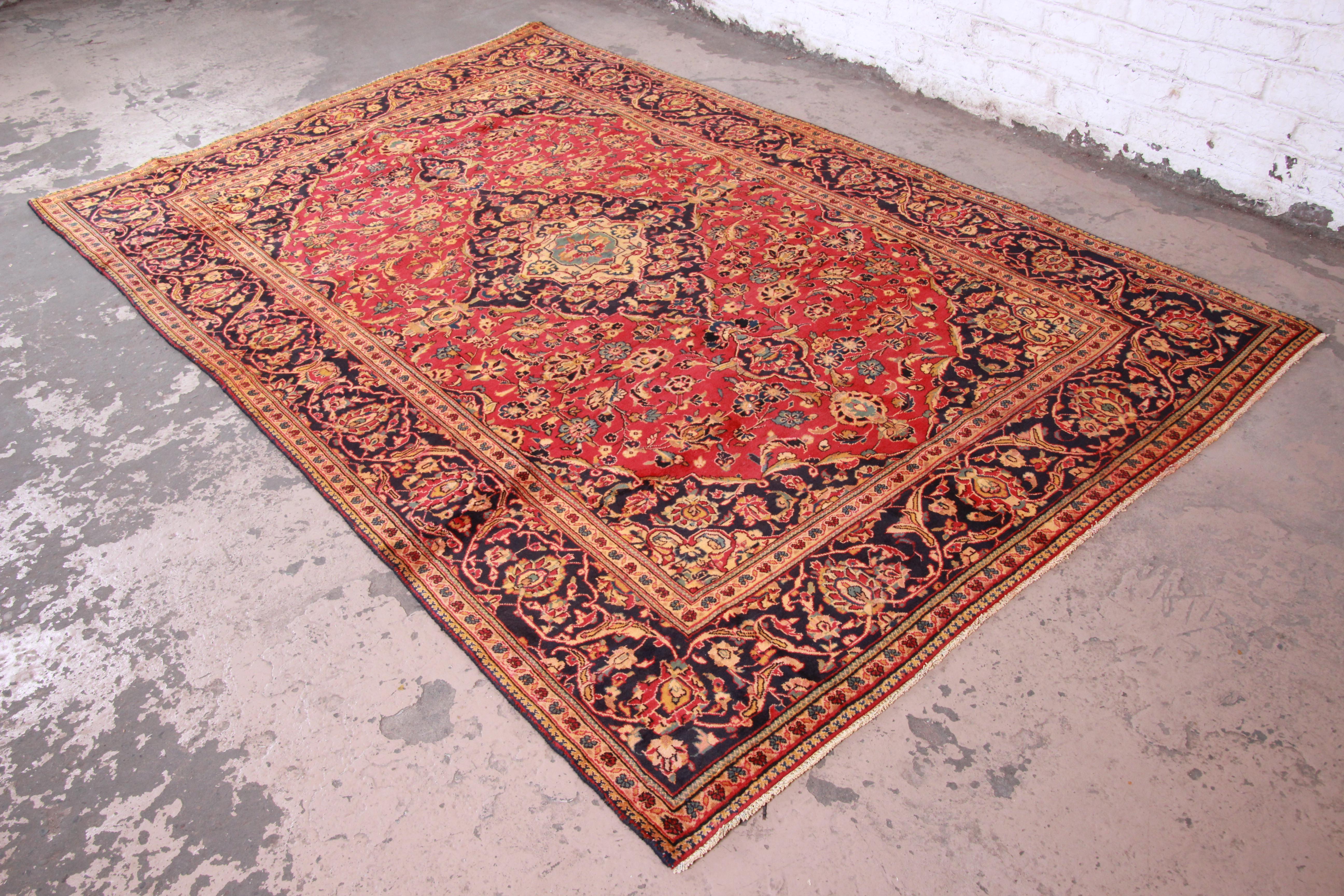A gorgeous vintage handwoven Persian wool rug. The rug has a 100% wool pile and a beautiful floral pattern with predominant colors in red, blue, and gold. The rug is clean and in very good condition. Ready for immediate use.

The rug measures 77