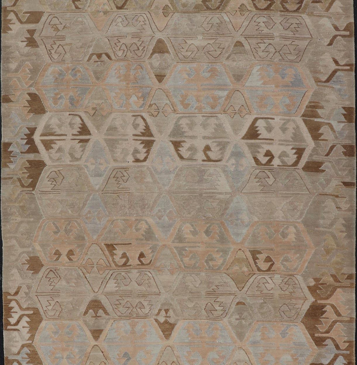 Dieser flachgewebte türkische Stammeskelim wurde von Hand aus Wolle gewebt. Der Teppich zeichnet sich durch ein subgeometrisches Muster aus, das in grauen, blauen und erdigen Tönen gehalten ist und sich hervorragend in eine Vielzahl von Innenräumen