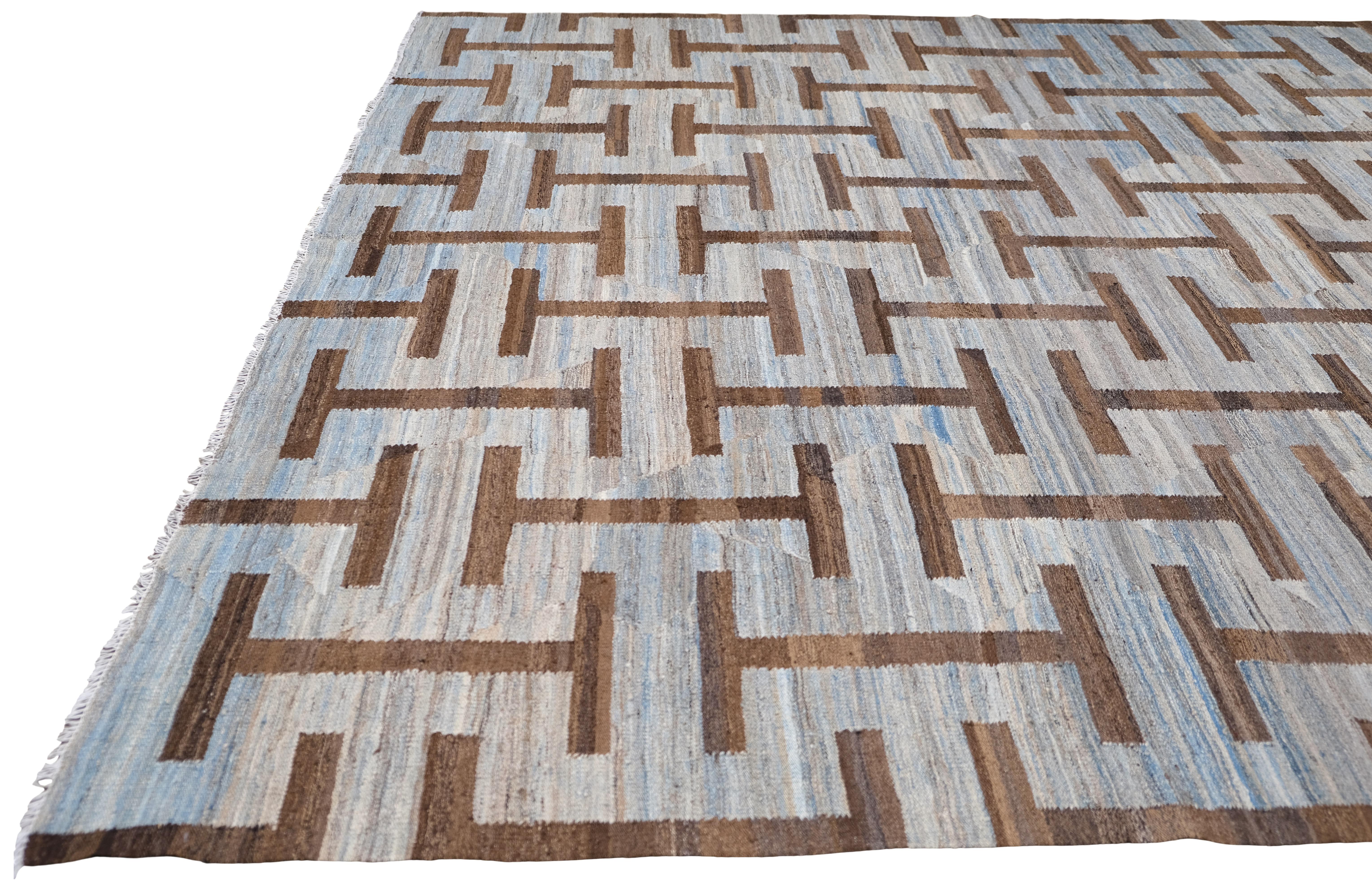 Ce tapis en laine tissé à la main au Pakistan est un mélange harmonieux d'artisanat traditionnel et de design moderne. Doté d'un motif géométrique accrocheur dans des tons doux et terreux, ce tapis ajoute un élément architectural unique à n'importe
