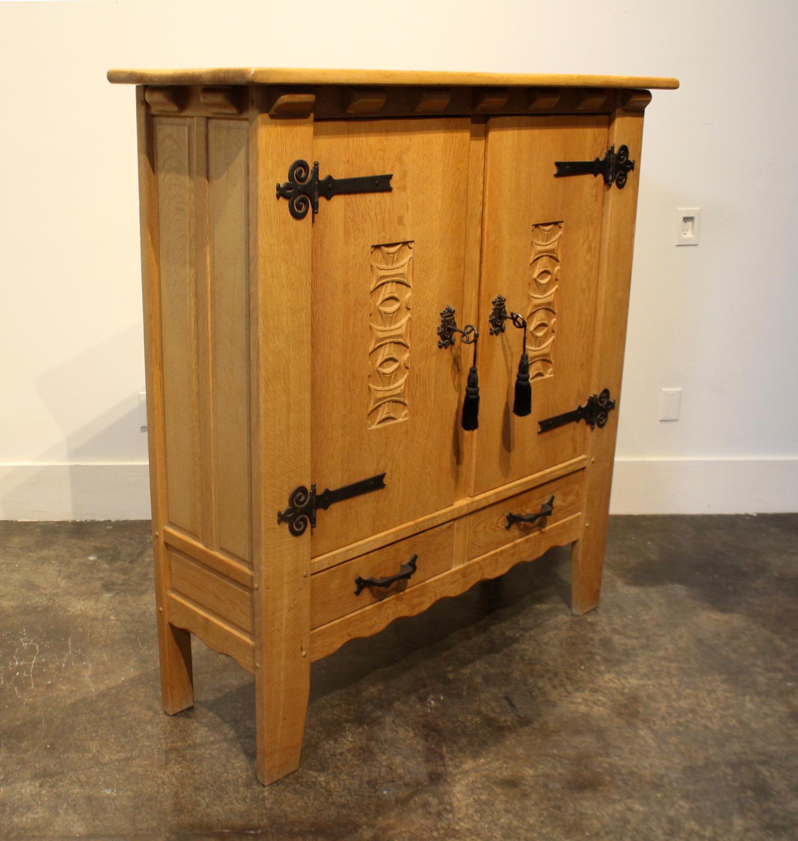 Beautifully crafted, Mission-style, solid-oak cabinet with wrought iron hardware . Comes with two inner shelves and two pullout / pull-out drawers. Front doors carved with Maltese cross motif.