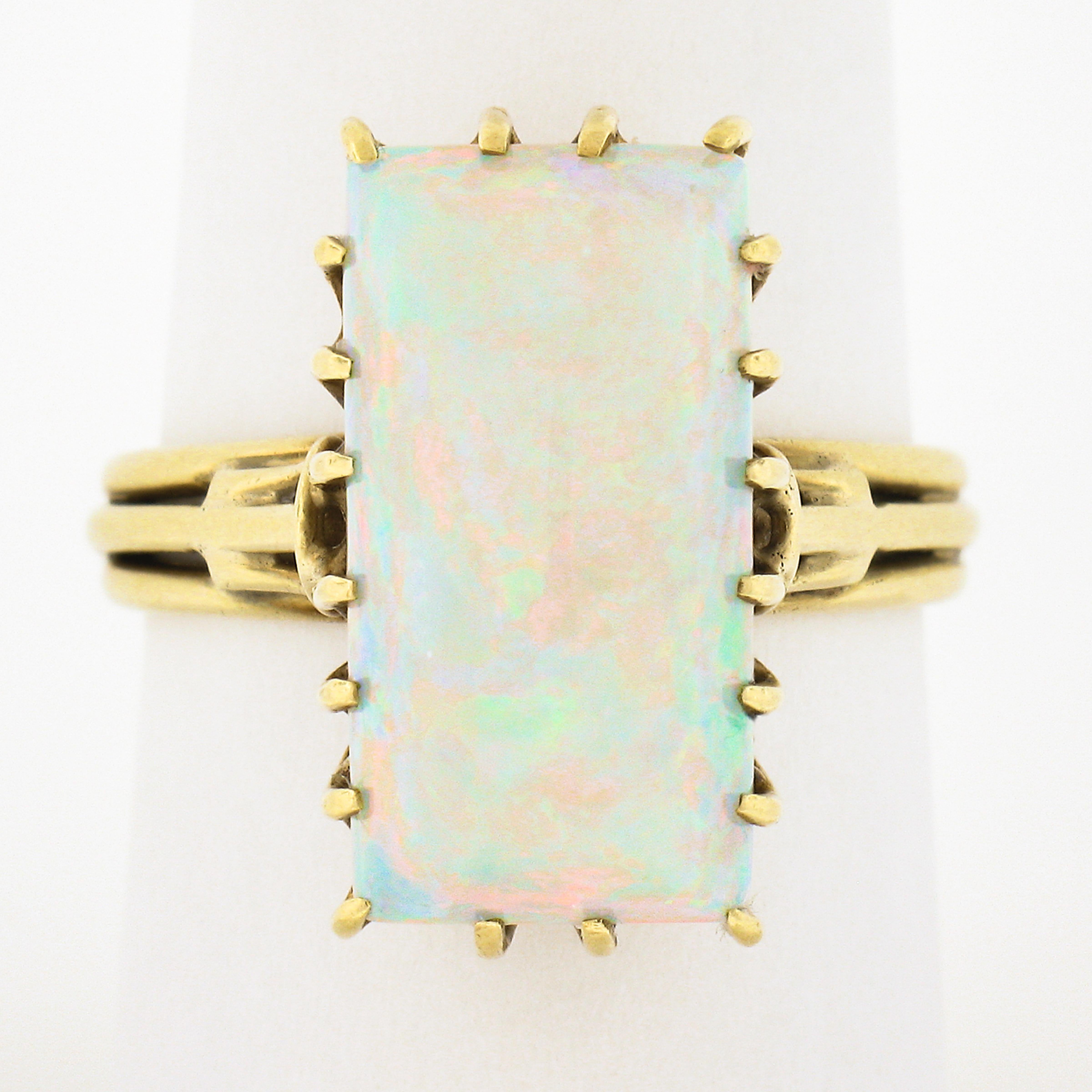 This spectacular, handmade, vintage ring is crafted in solid 18k yellow gold and features a breathtaking opal gemstone neatly and elegantly multi-prong set at the center of the open wore basket setting. The white opal has no crazing, and displays