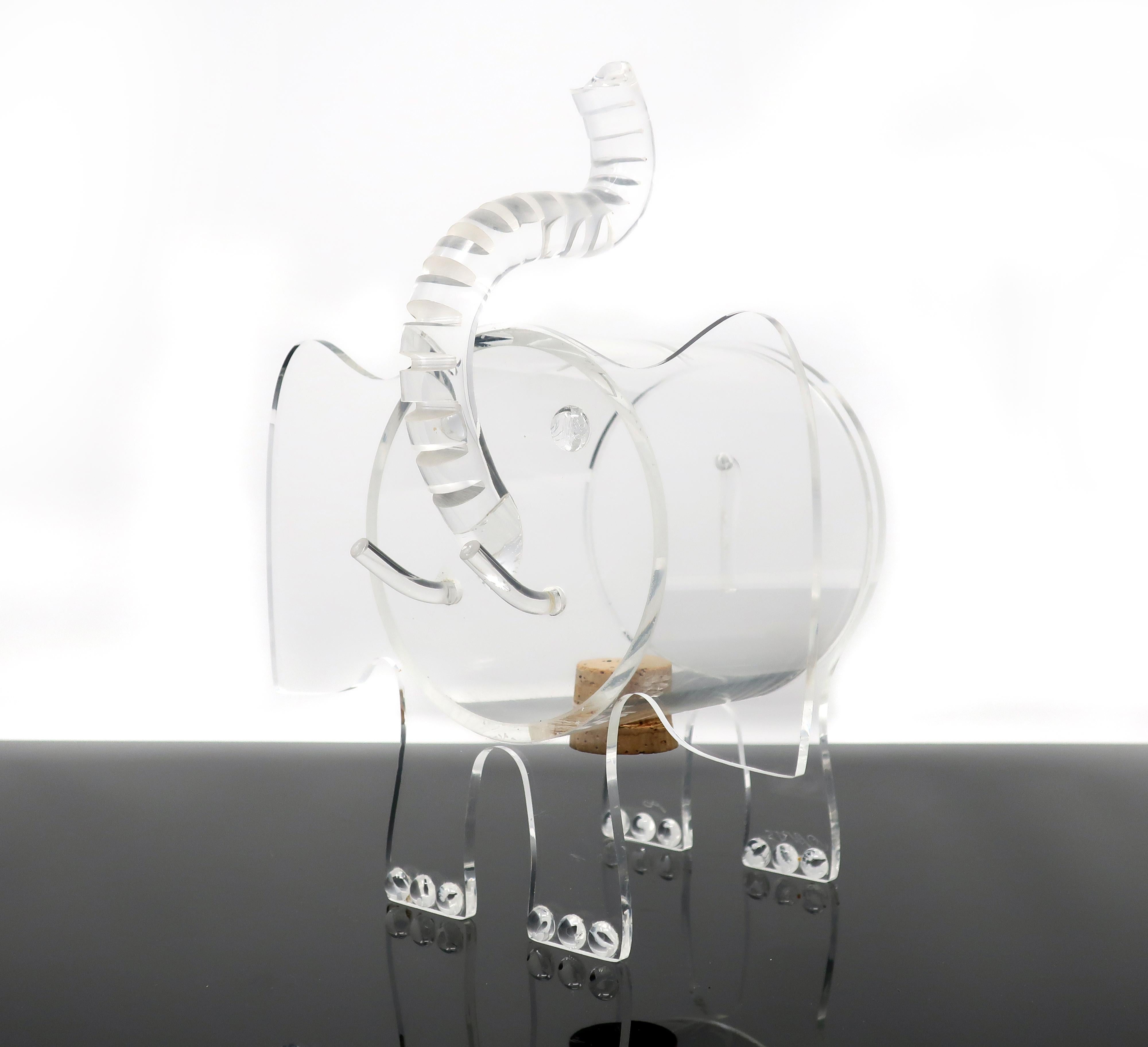 A handmade acrylic piggy bank in the shape of an elephant. The exaggerated ears and upturned tusk give this piece a charming personality. There is a slit in the top of the body for coins to be dropped in, and a cork-plugged hole on the underside