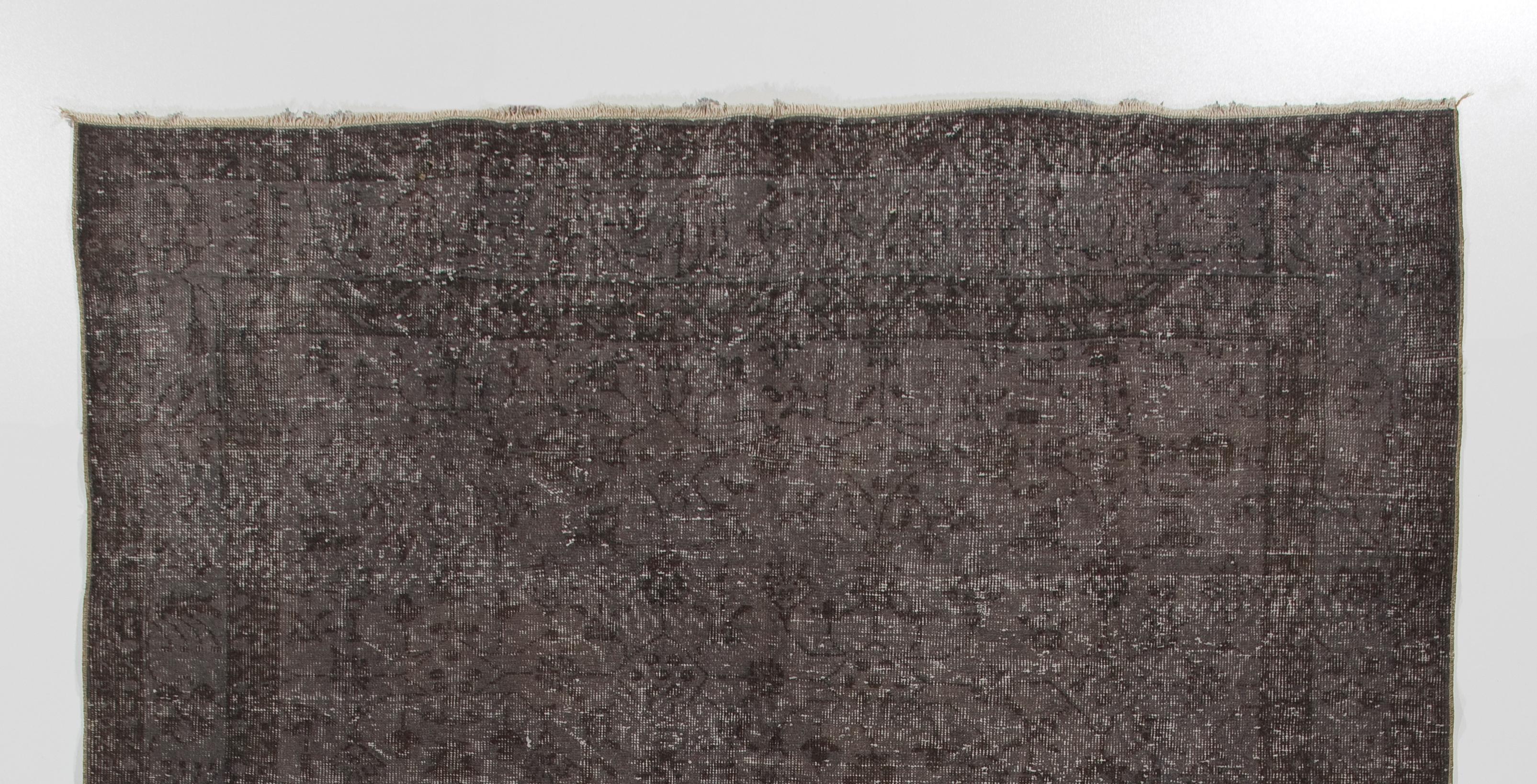 Un tapis vintage noué à la main en Turquie dans les années 1960. Le tapis est composé d'un velours de laine à poils courts et d'une base en coton. Il est surteint en gris taupe et présente un motif floral sur toute sa surface. Il est en bon état,