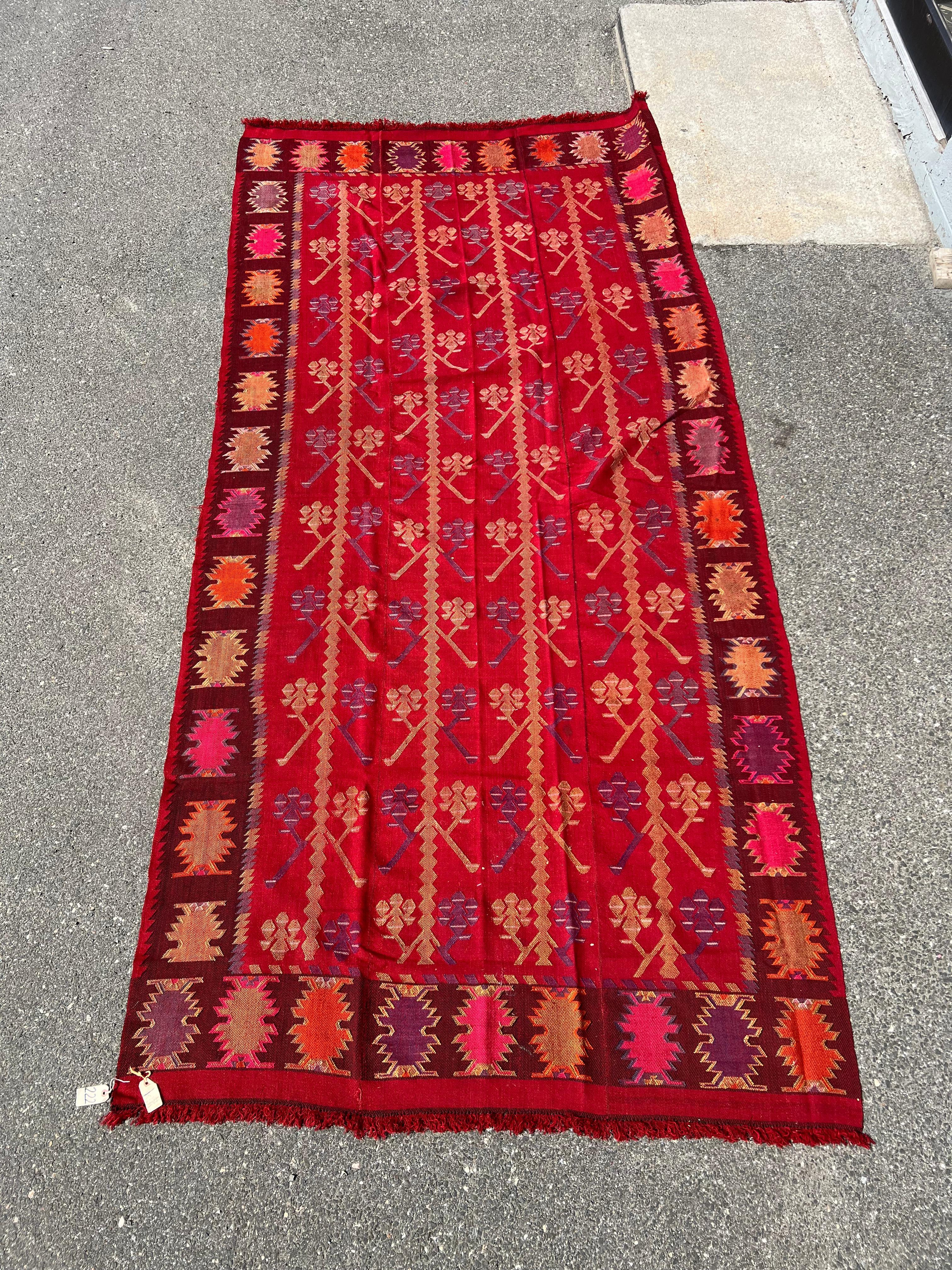 Vibrante y folclórico, este kilim tracio búlgaro de principios del siglo XX hecho a mano es una alegre celebración del color y la tradición. Tejida en una llamativa trama plana, la pieza presenta hileras de estilizados motivos del árbol de la vida