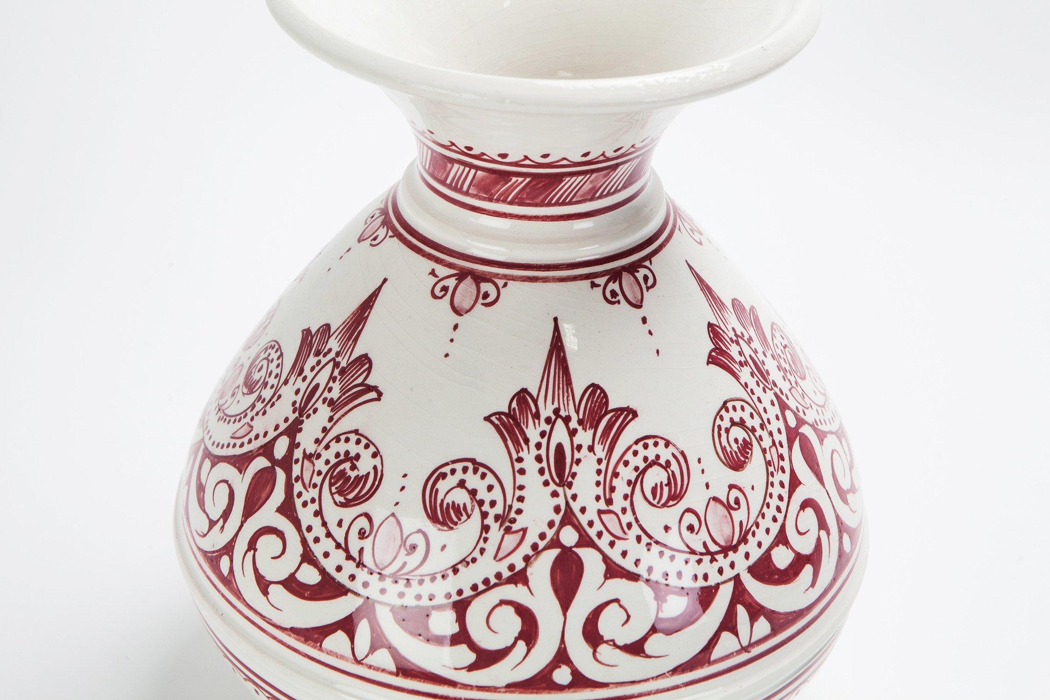 A vintage handcrafted Moroccan burgundy and white ceramic vase, featuring intricately swirling hand painted designs, this vase provides a touch of exotic sophistication that will accentuate any room. It has been created by master artisans working