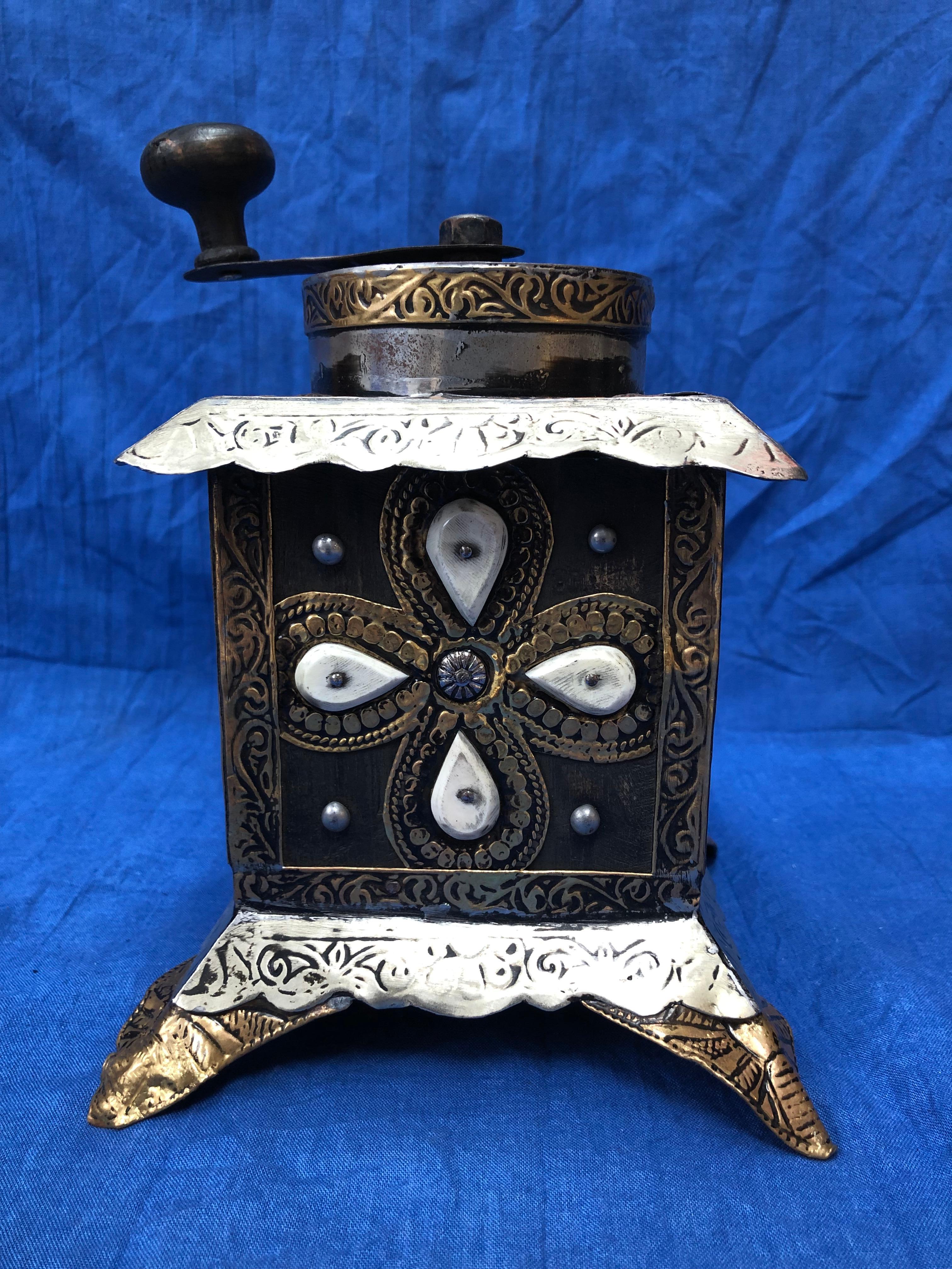 This vintage coffee grinder is made of ebony wood, with hand-engraved silver melange and brass adornment, hand carved camel bone embellishments, and a handhewn grinding mechanism. 

Entirely handmade, this grinder was used by southern Morocco