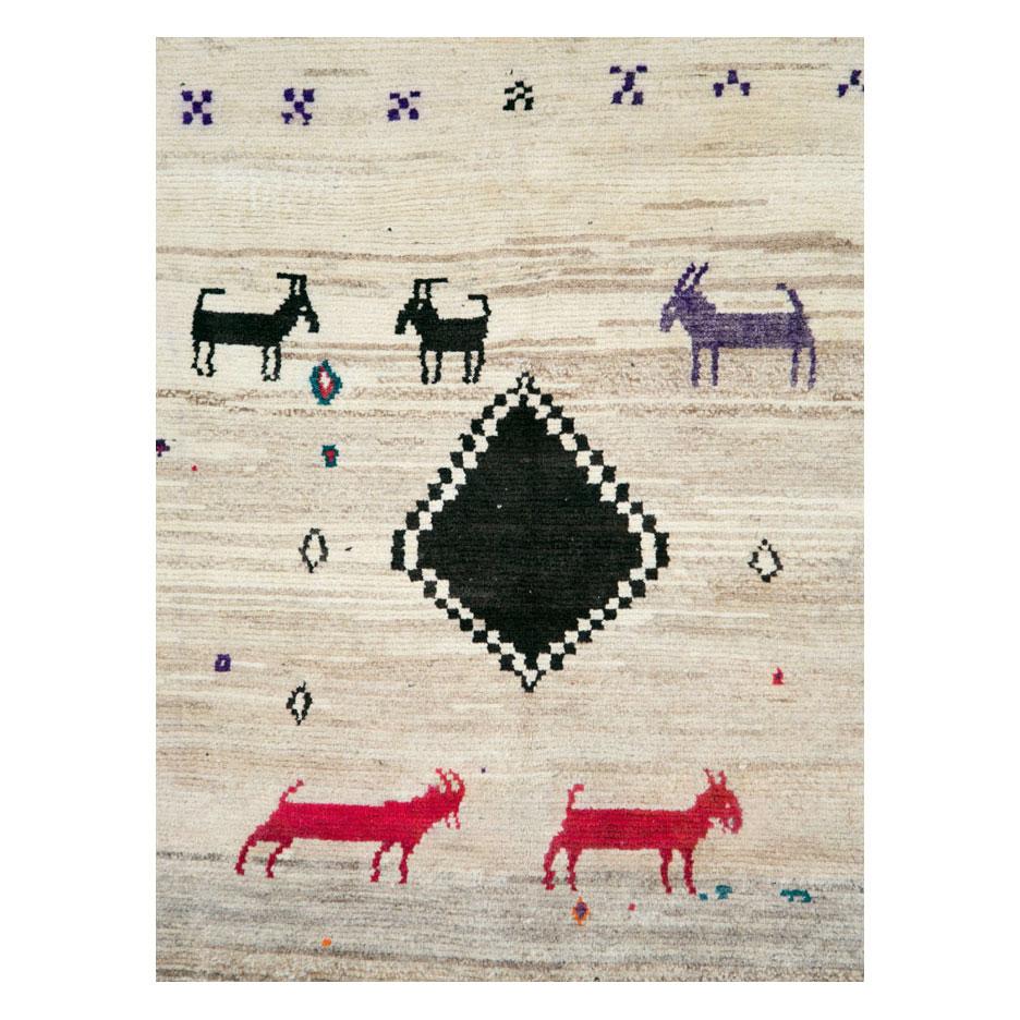 A vintage Persian Gabbeh rug handmade by the nomadic Qashqai Tribe during the late 20th century. Animals scattered about the cream white field surrounding an offset black medallion. The horse or donkey-like figures are in black, purple, red, orange,
