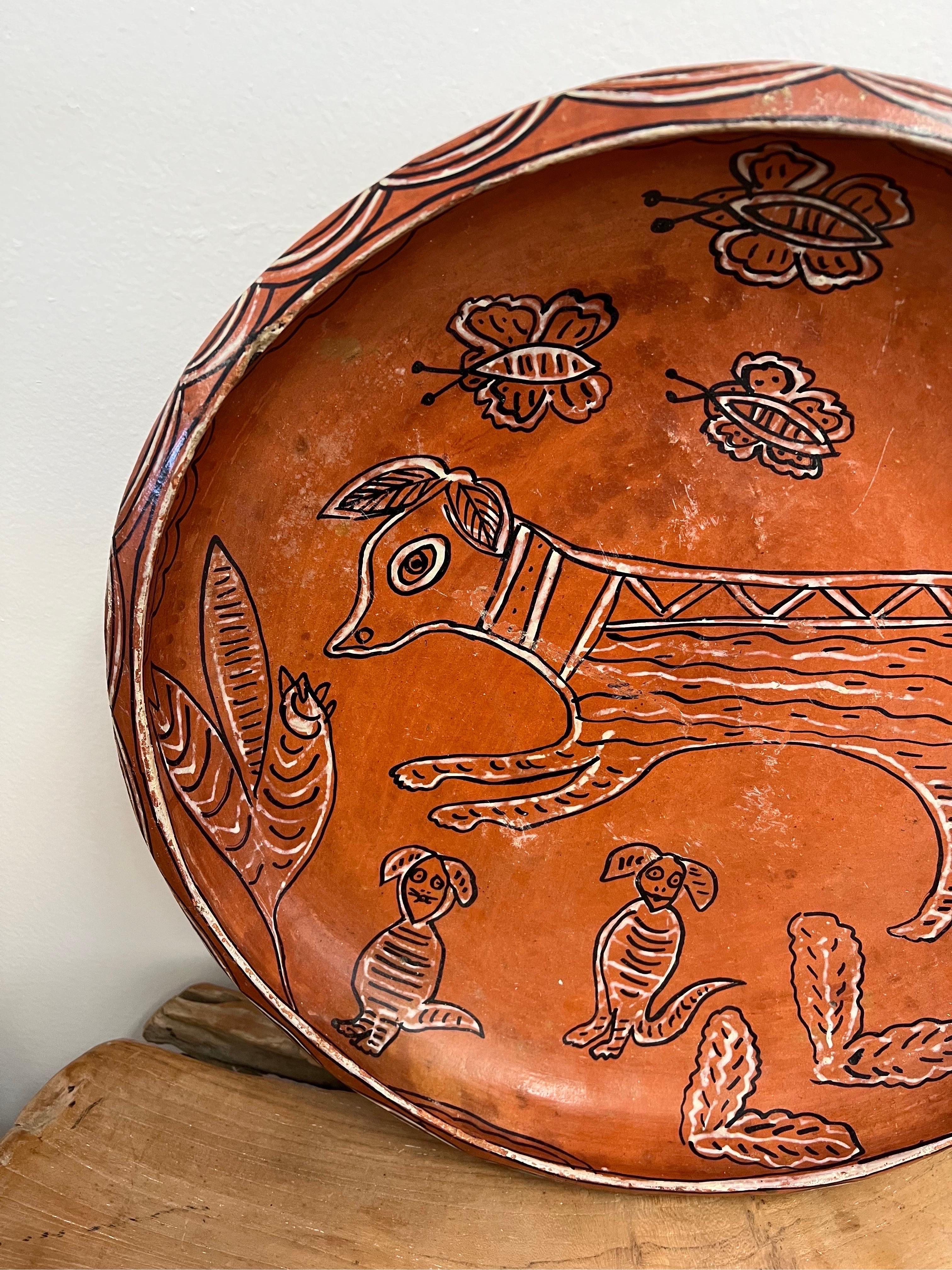 Vintage handmade pottery with hand painted animal motif in a terracotta orange color.

Dimensions. diameter 17 1/2 ; 2 3/4 depth.