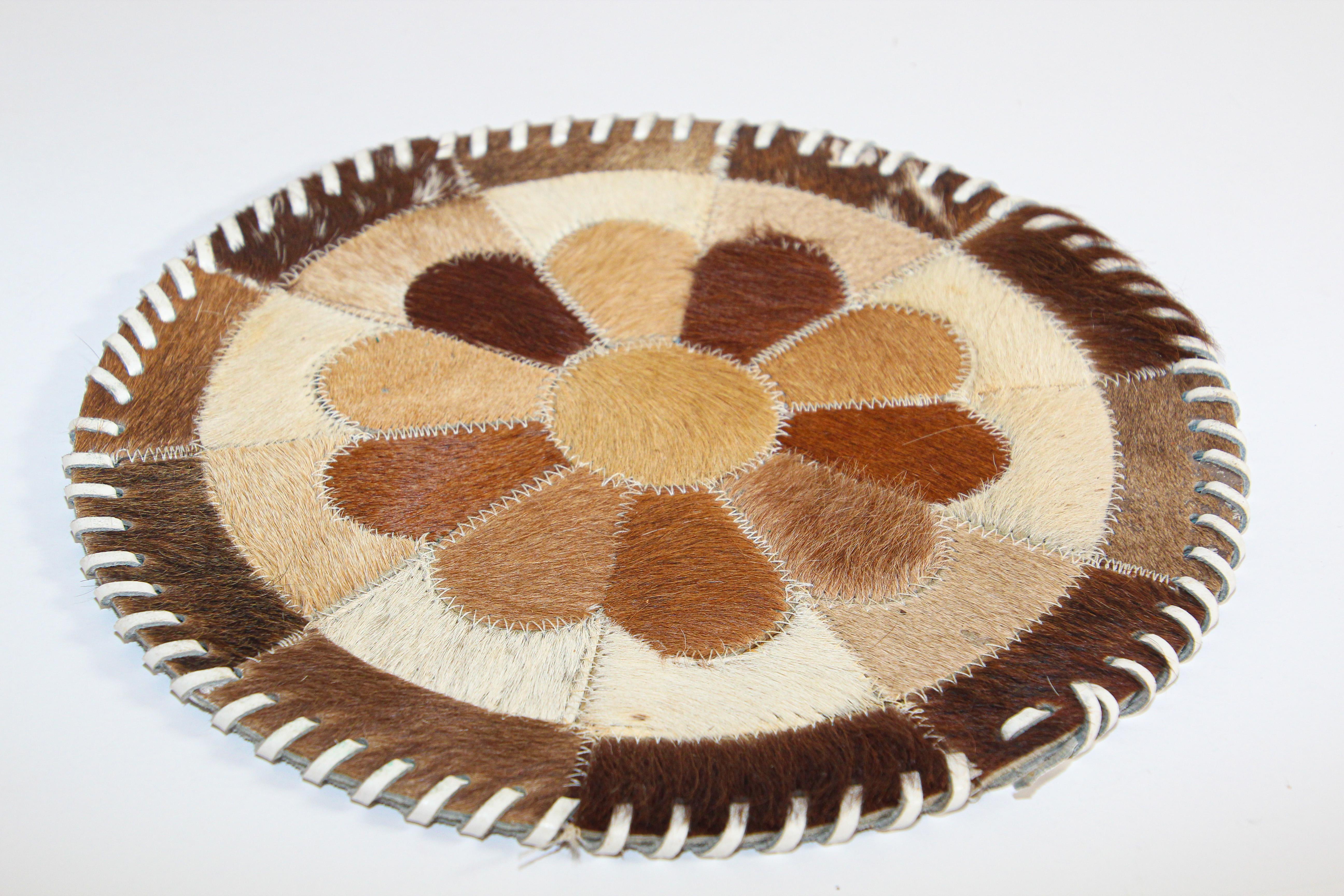 Handmade vintage south western leather cow hide round table mat.
Cowhide patchwork handcrafted from small pieces of leather and sewn together to create a beautiful pattern in shades of brown and white with white leather lacing.
The material is