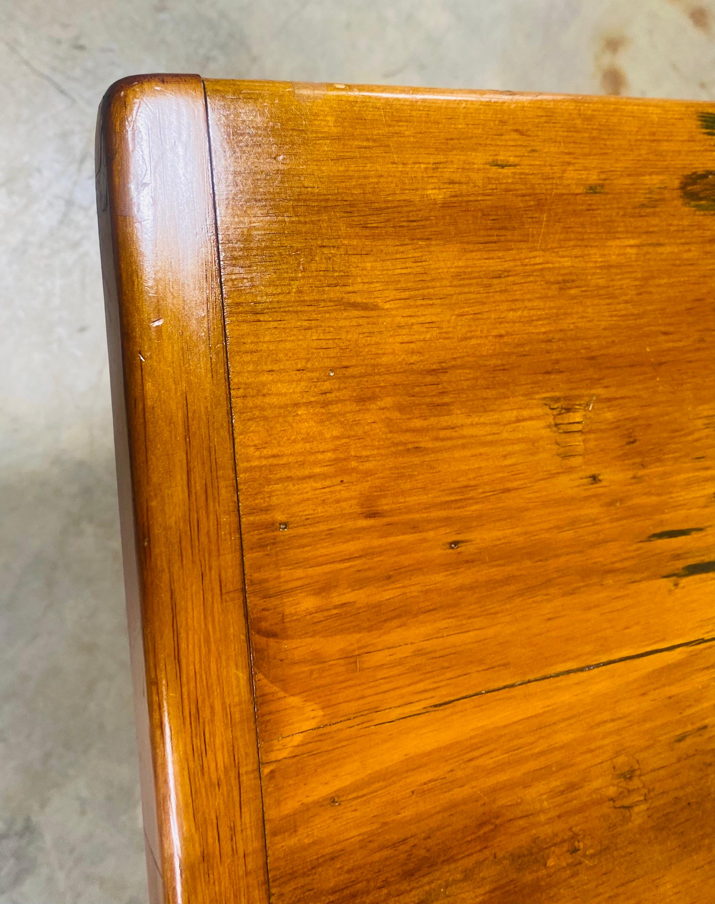 This is a vintage handmade rustic farmhouse style dining table. This table is handmade with wide pine planks on the top with breadboard edges. The top of the table is removable with peg and hole construction. This rustic pine table is American made