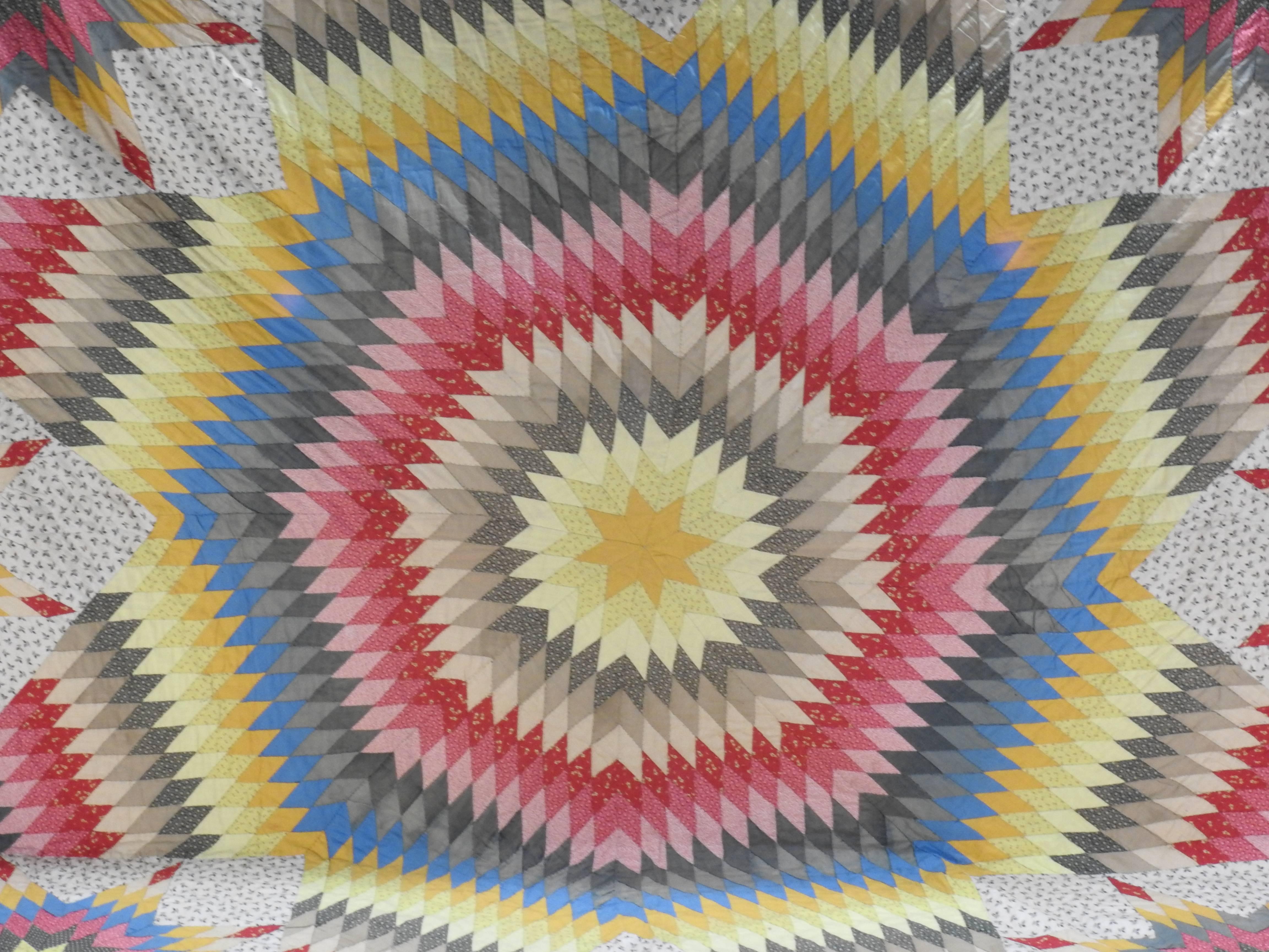 Vibrant colors make up this beautiful handmade vintage quilt. This quilt features a large star design in the center of the quilt with small stars between each of the eight points on the star. This design is made of a variety of colored cotton blend