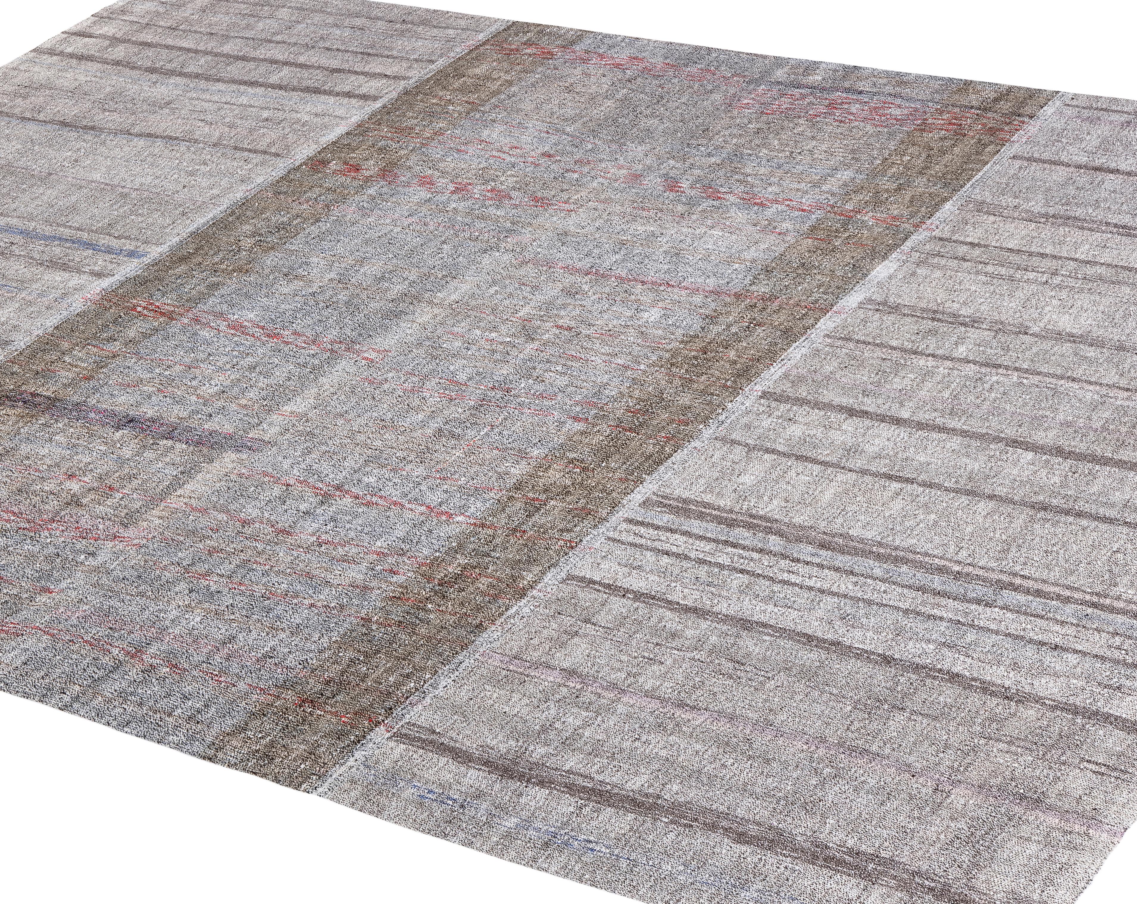 This Mid-Century Modern flatweave rug is handwoven in Iran using handspun wool and natural, organic dyes. Its palette of soft grey and cream undyed tones is enhanced with subtle linear accents, creating a minimal yet sophisticated design inspired by