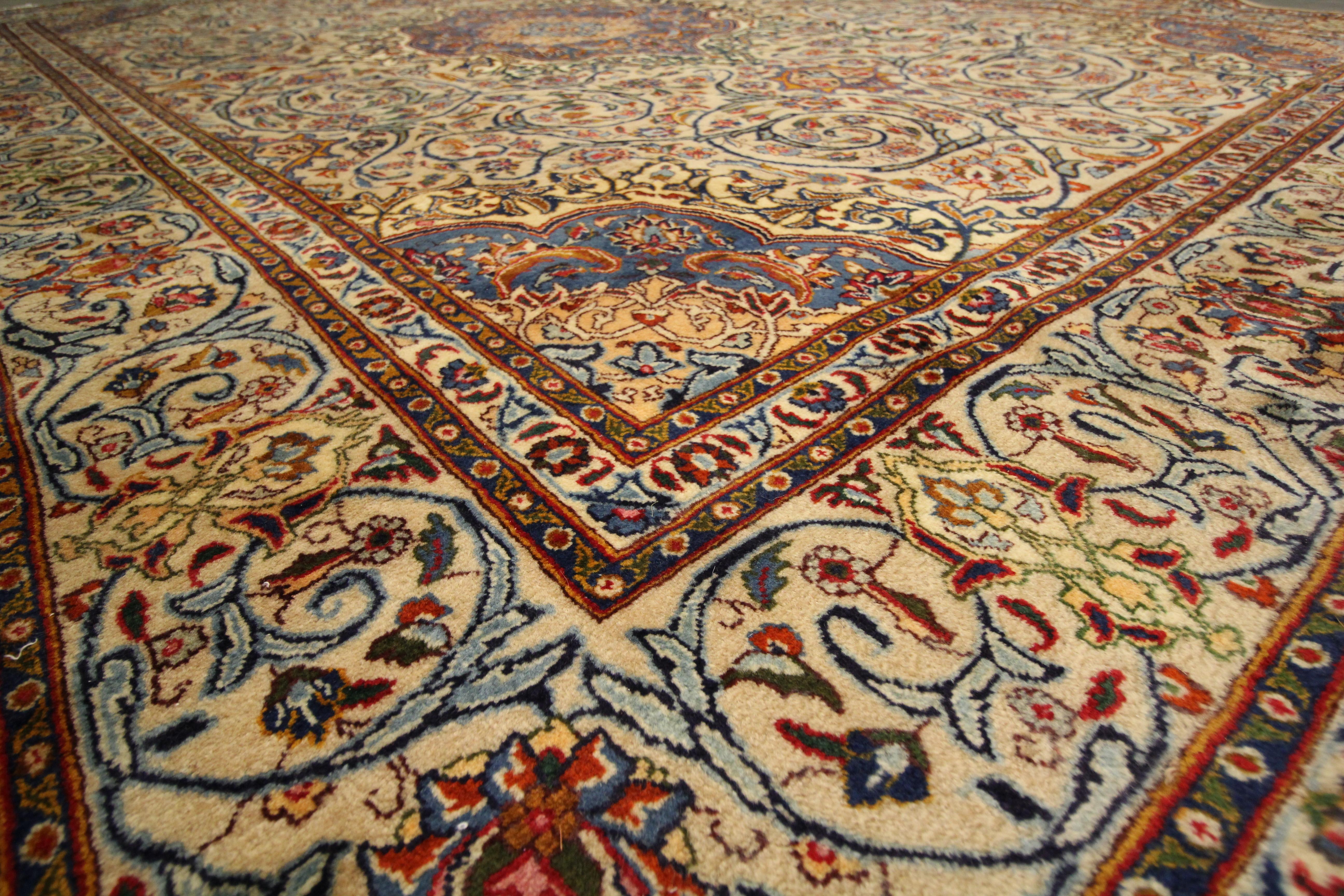 This fine wool area rug is a fantastic example of vintage rugs woven in the mid 20th century, circa 1950. This piece has a unique colour palette and bold, symmetrical design. Woven with a cream background and blue, golf, rust and brown accents that