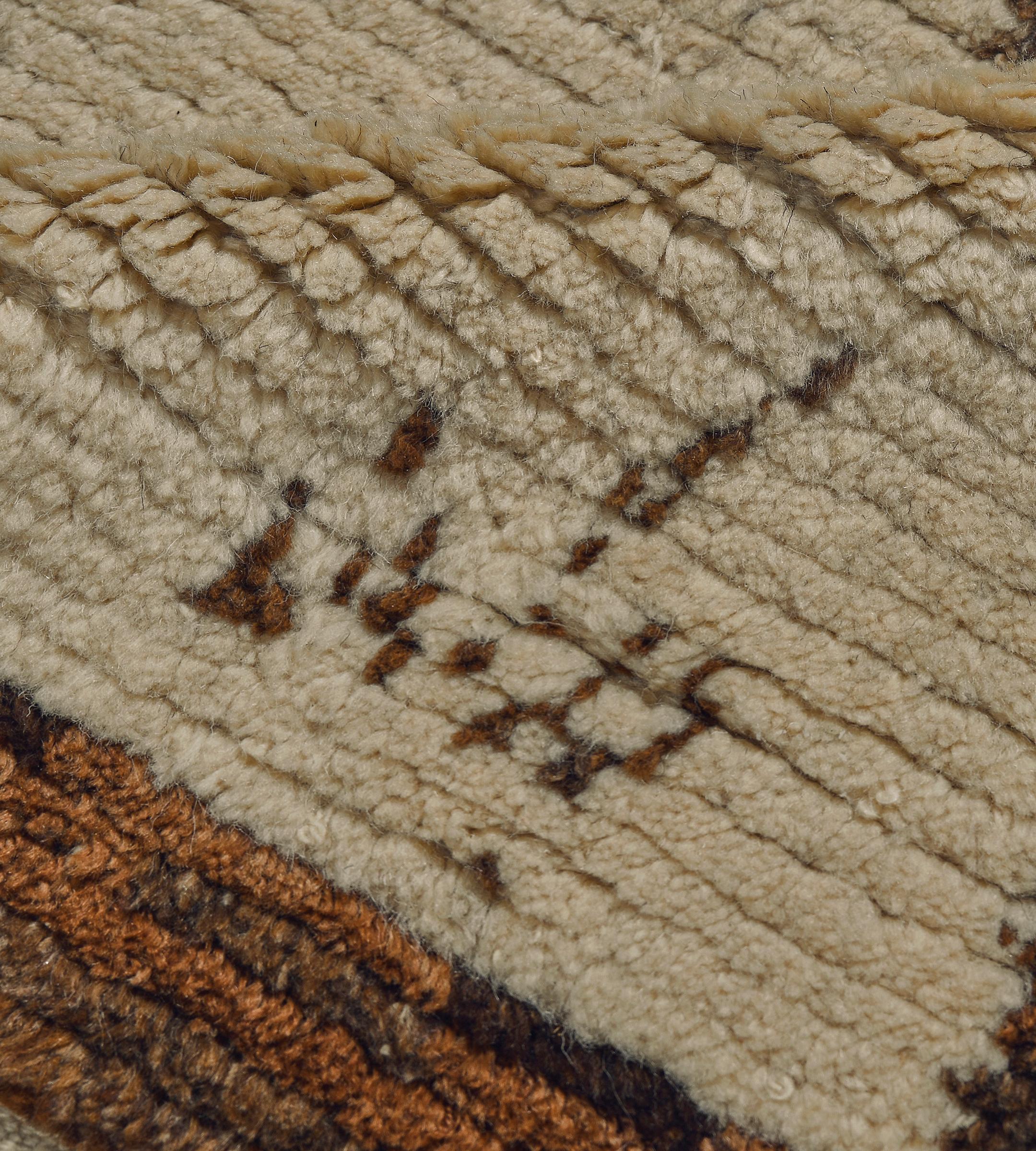 This vintage, circa 1970s, hand-knotted wool and hemp Moroccan rug features a natural wool colored field with a shaded chocolate-brown linked lozenge pattern each lozenge containing a single angular chocolate-brown floral motif, the sides with a