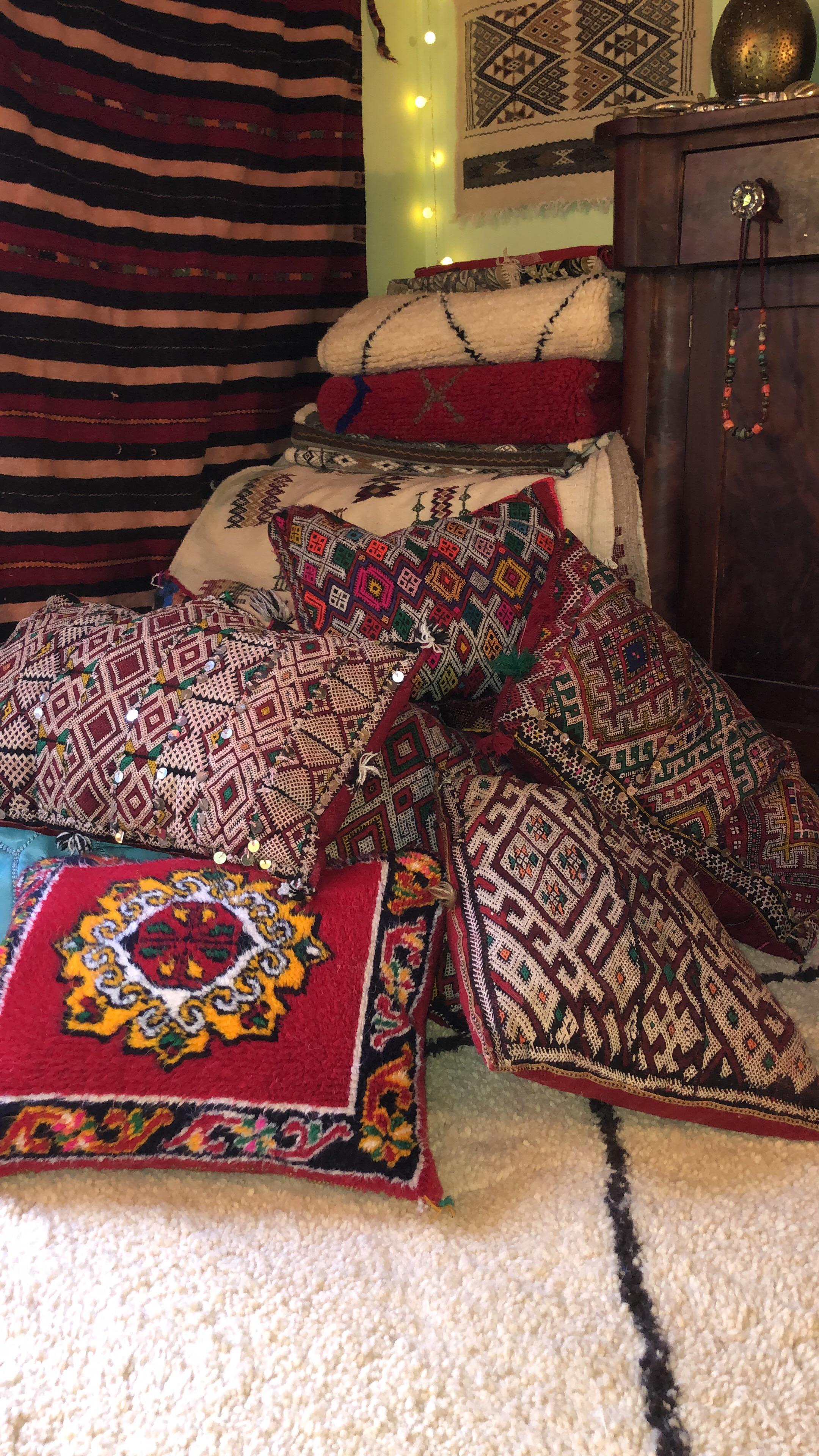This complex handmade pillow adds an exotic Bohemian feel to any room. Decorated with geometric designs that mimic Berber tribal tattoos, as well as other symbolic imagery like the evil eye. Each pillow is one-of-a-kind, handwoven by Moroccan
