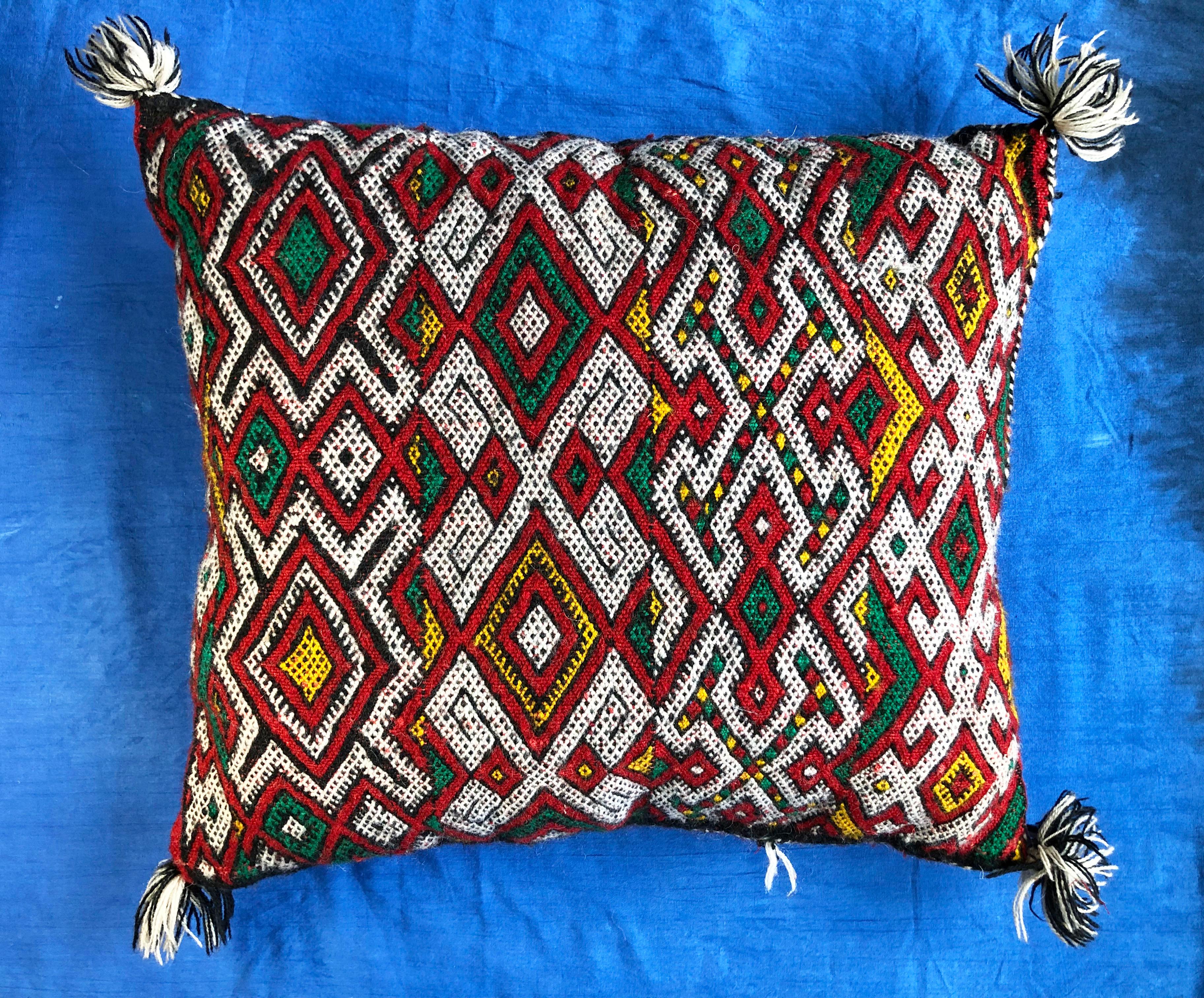 This vibrant, colorful handmade pillow adds an exotic Bohemian feel to any room. Decorated with geometric designs that mimic Berber tribal tattoos, as well as other symbolic imagery like the evil eye. Each pillow is one-of-a-kind, handwoven by