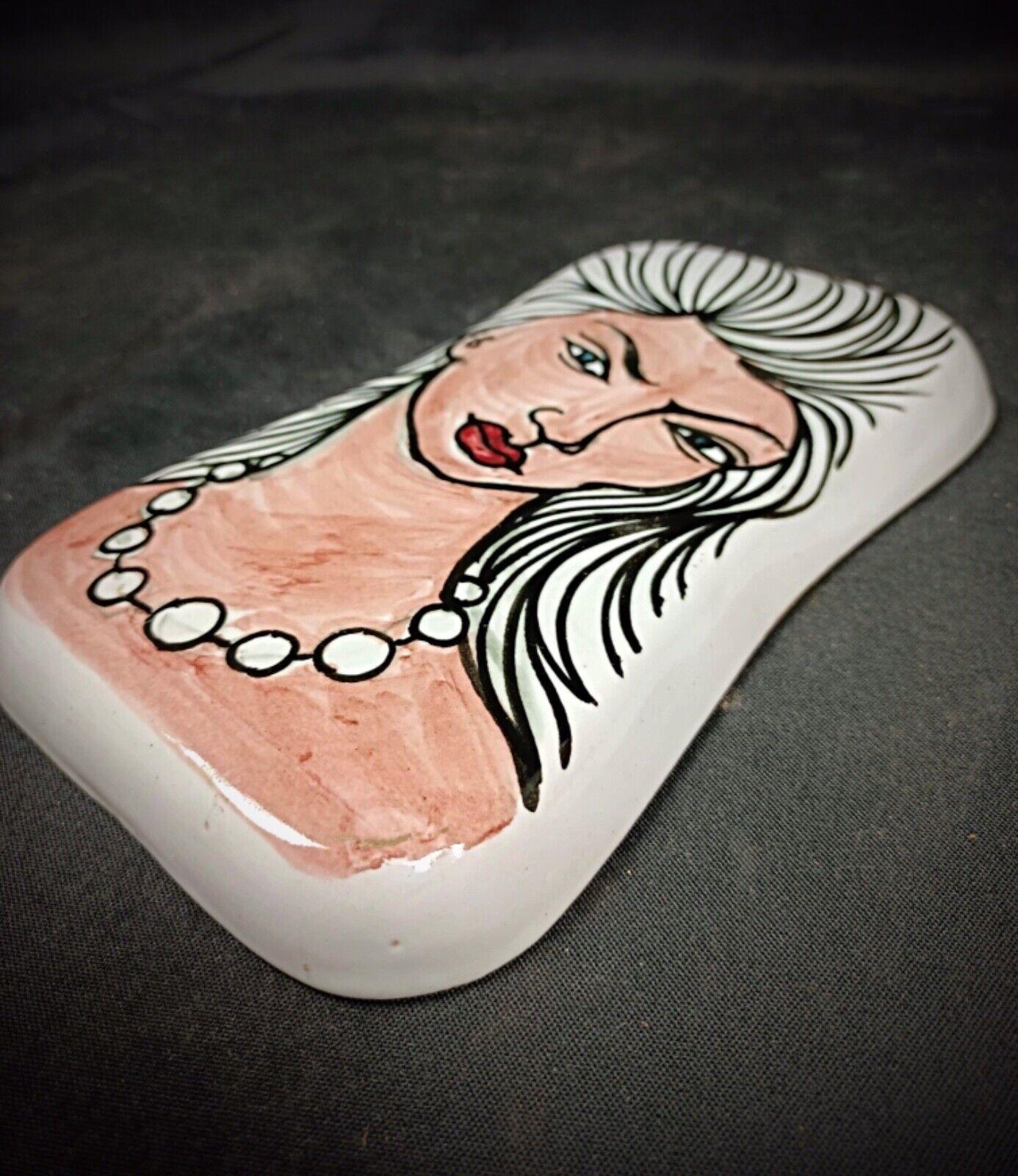 Questa squisita scultura vintage appesa di Igor S. Stéphano cattura l'eleganza e la grazia di una donna con dettagli sorprendenti. Realizzata in ceramica e porcellana, la scultura presenta vibranti finiture multicolore che ne esaltano il fascino